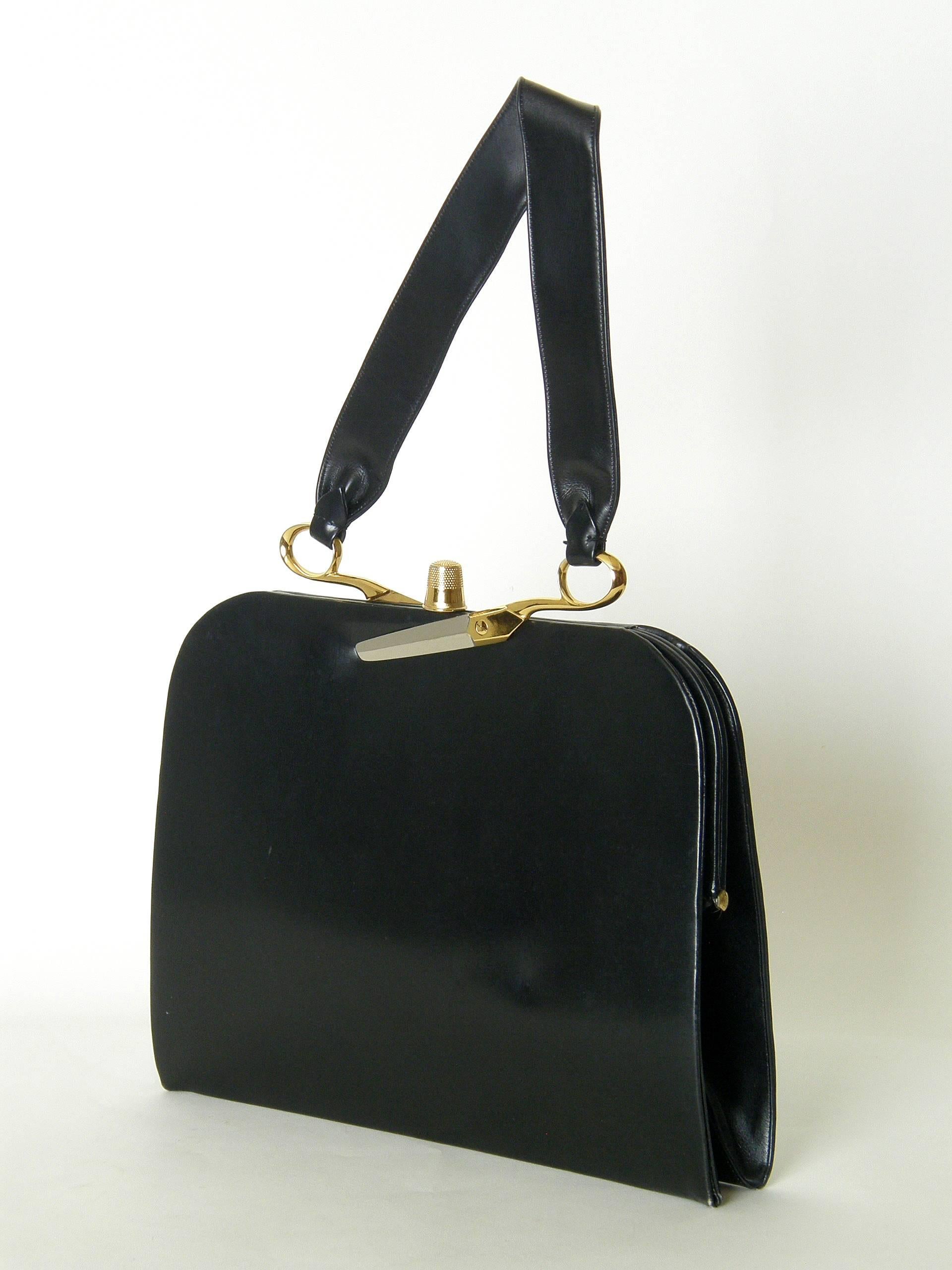 This exceptional Koret black leather handbag has dissected scissors attaching the handle to the frame and a thimble for the clasp. The yellow gold plated thimble and yellow and white gold plated scissors halves are extremely realistic. The black