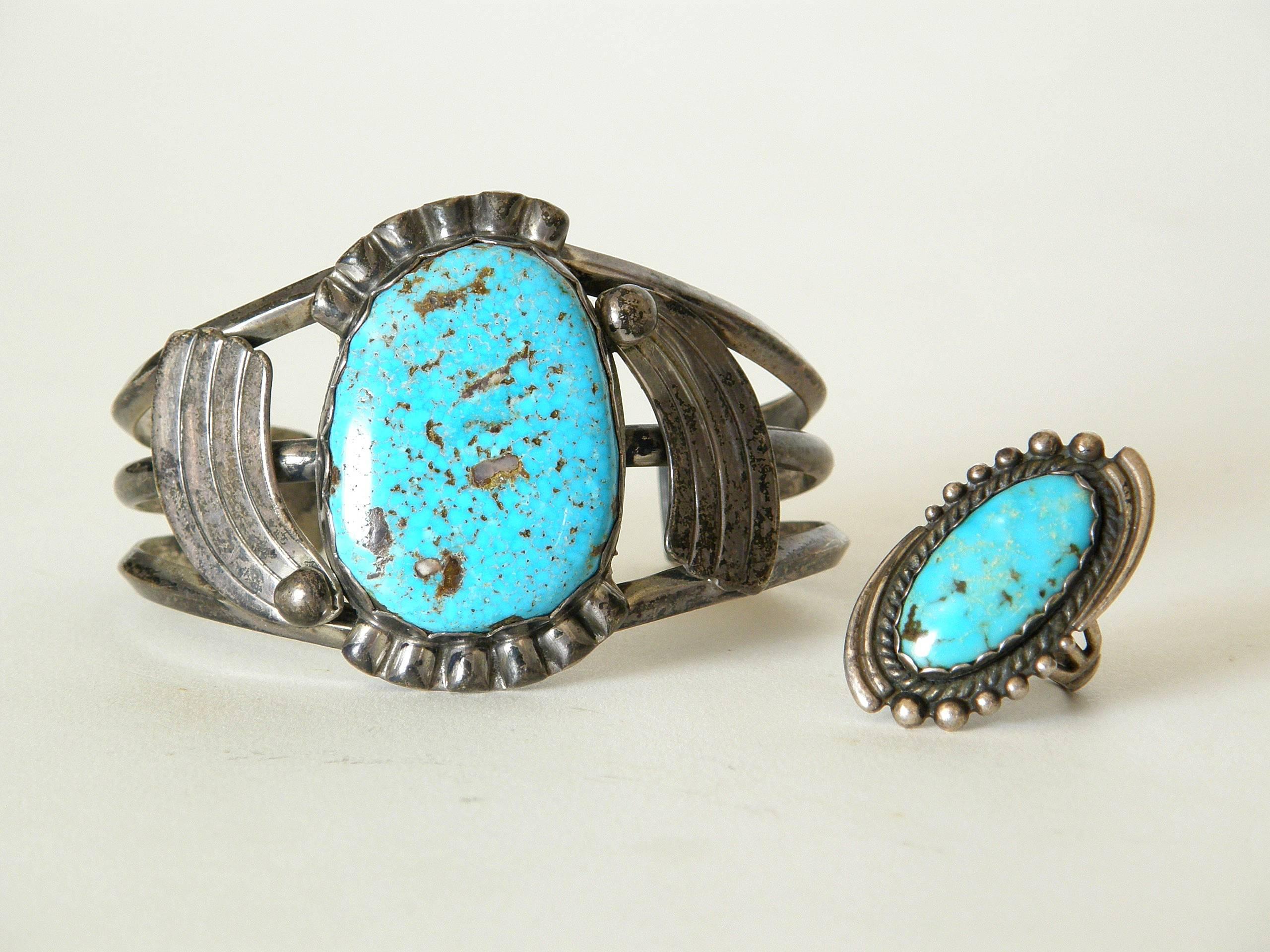 These c. 1940s or 1950s sterling cuff bracelet and ring are set with turquoise. The stones have scalloped bezel settings that are flanked by tapering bands that create a feeling of movement like shooting stars or a spinning effect. The ring and
