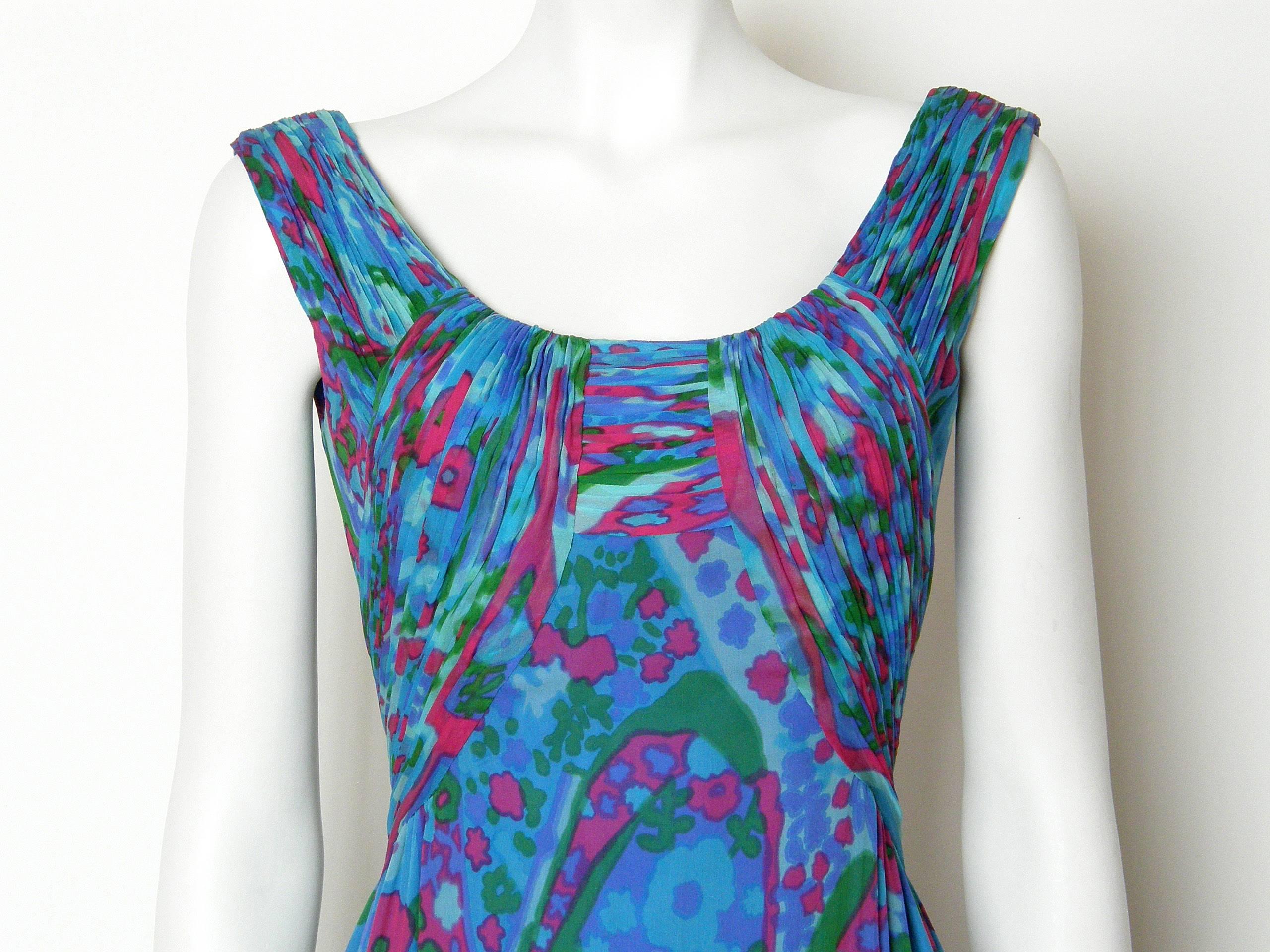 This colorful evening dress has a bold floral pattern on the silk chiffon. The sleeveless bodice has a wide rounded neckline in front and a deep 