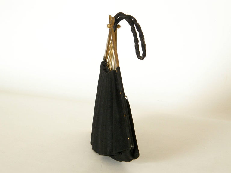 This sweet figural handbag is shaped like a folding hand fan. It's done in a fine, black suede on a frame of gold plated brass. A zippered opening allows access to the bag, and the satin lined interior has one little slip pocket.

Anne-Marie had a