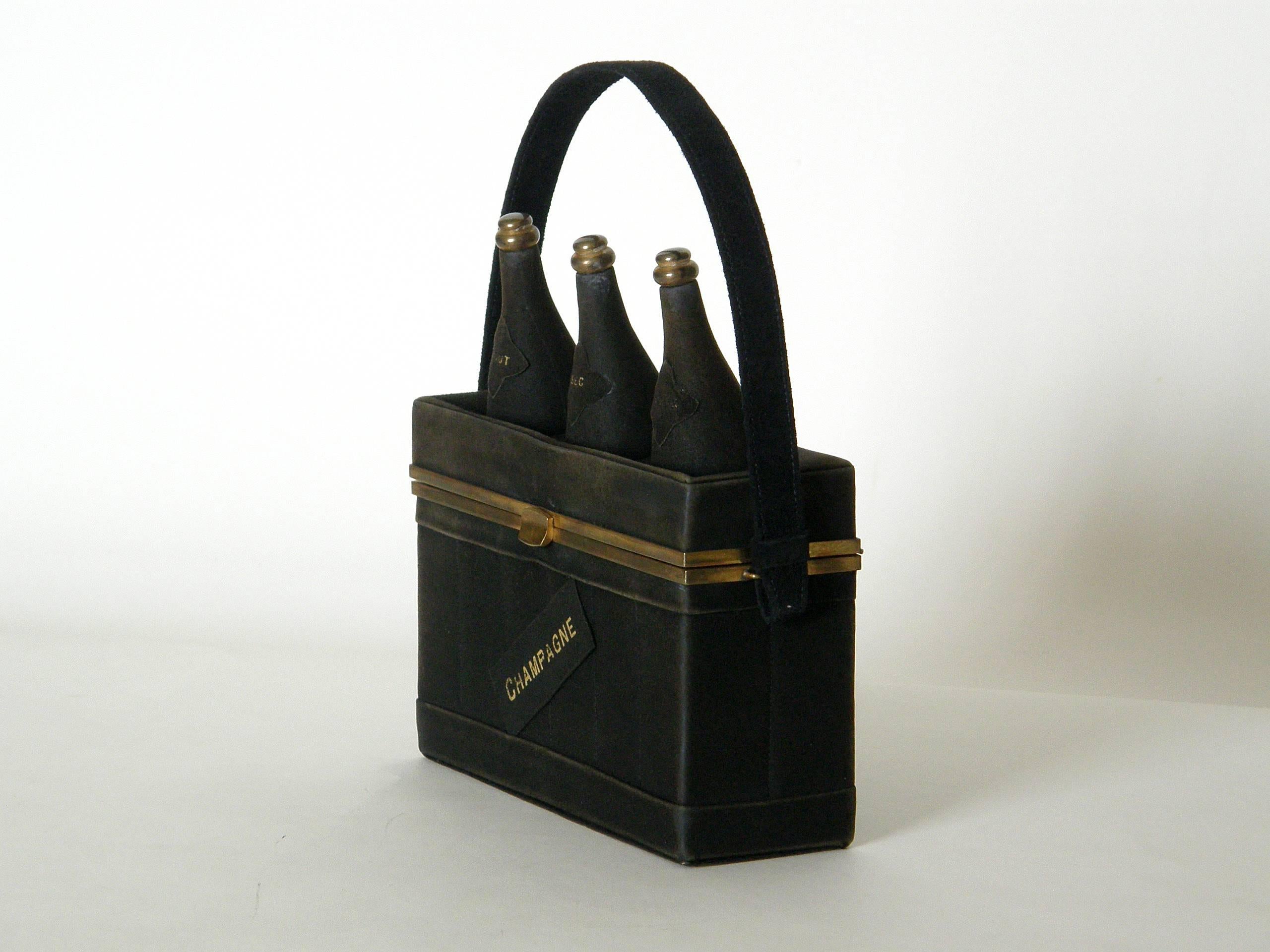 This wonderful figural handbag is shaped like a wooden crate with 3 champagne bottles sticking out of the top. Made from a fine black suede, the crate has a label on the front stamped 