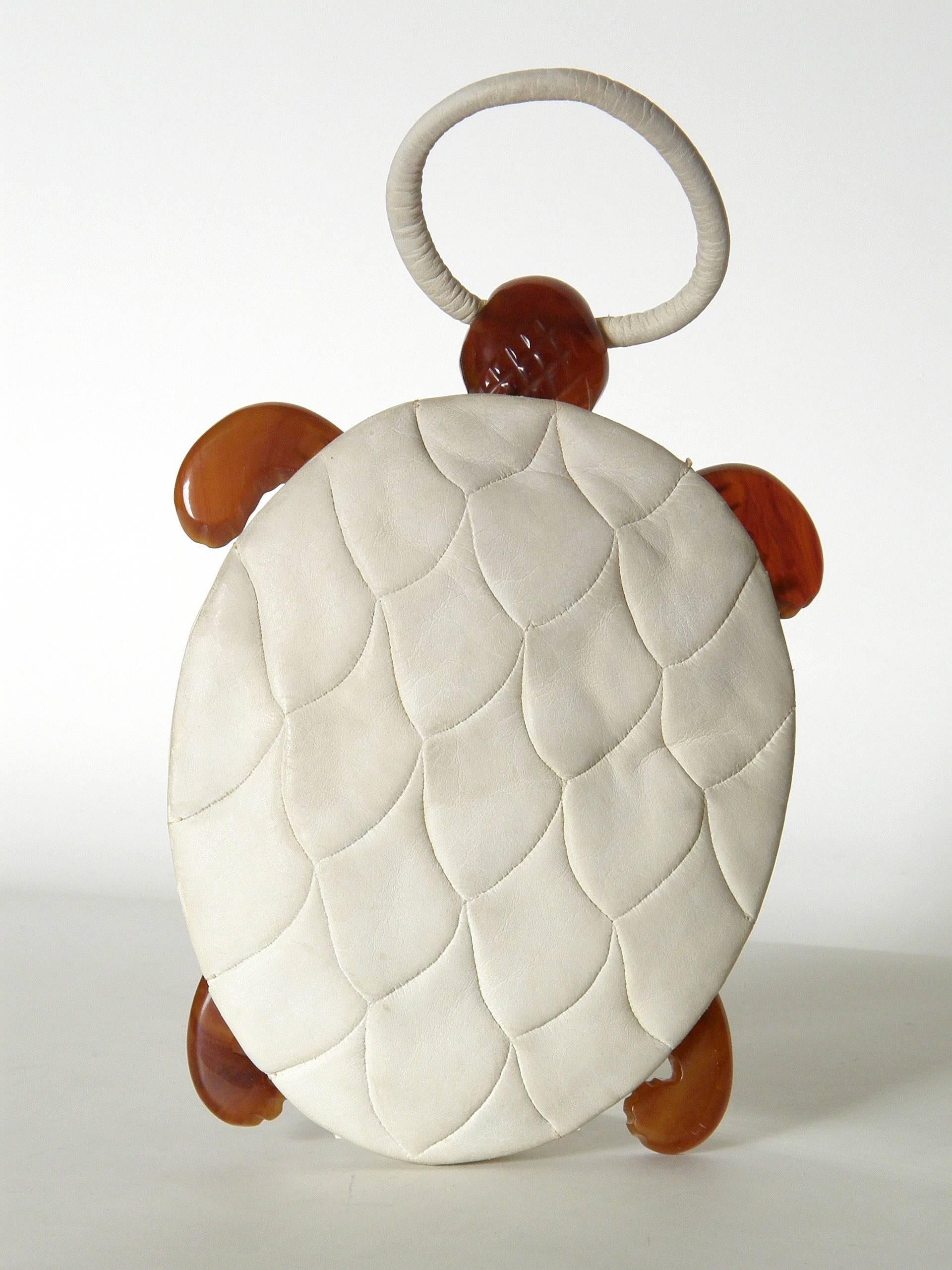 This adorable turtle shaped handbag has wonderful details. The body / shell of the turtle is done in soft, cream colored (kid?) suede. The back is pieced to resemble the pattern and texture of a turtle shell with plates. The belly of the turtle is