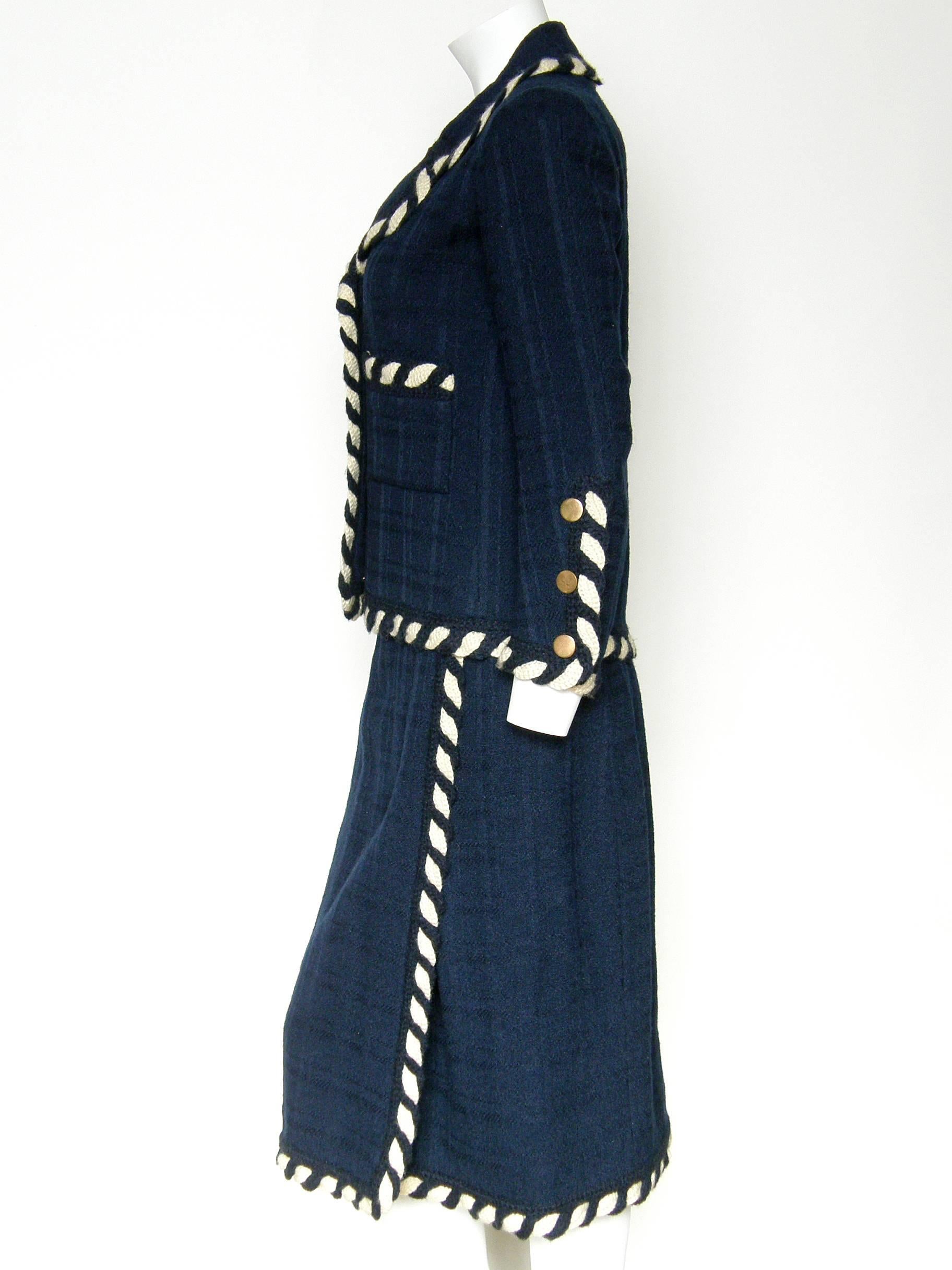 Classic, c. 1960s haute-couture suit by Chanel. The wool fabric has a subtle all navy blue, textured weave like a monochrome plaid. The jacket and skirt are accented with handmade cream and navy braided trim. They are meticulously constructed with