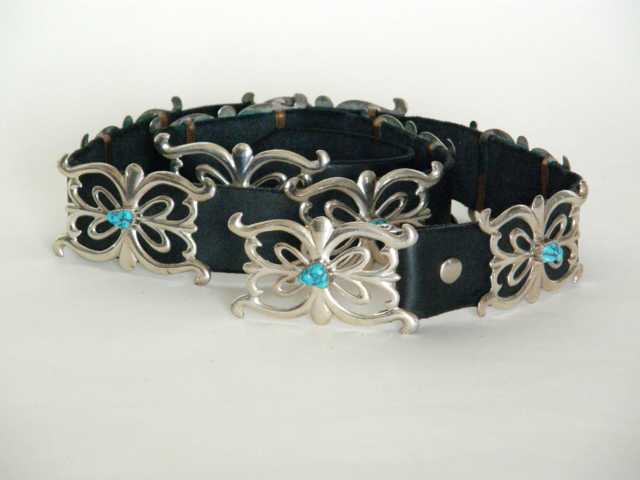 Black leather belt featuring ten sandcast sterling conchos, including the buckle, that are set with turquoise stones. This piece is probably Navajo. It has not been worn. It's never had holes punched in the leather, so they can be custom placed to