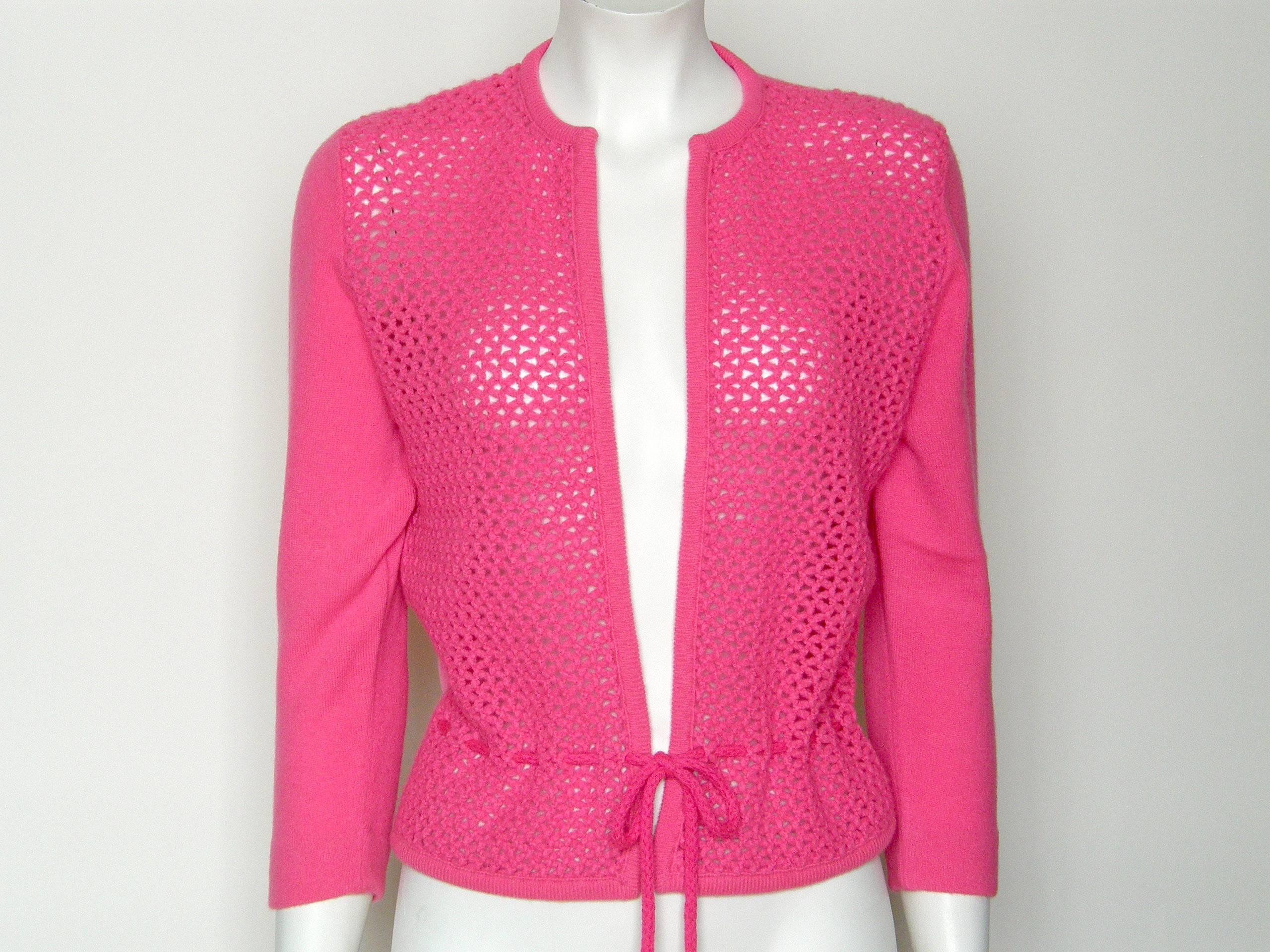 This vibrant pink cardigan has an unusual fishnet pattern on the front that highlights and flatters your curves. The braided tie laces through the openings in the net. As shown, the tie is hidden in back, but it can also be laced so that it goes