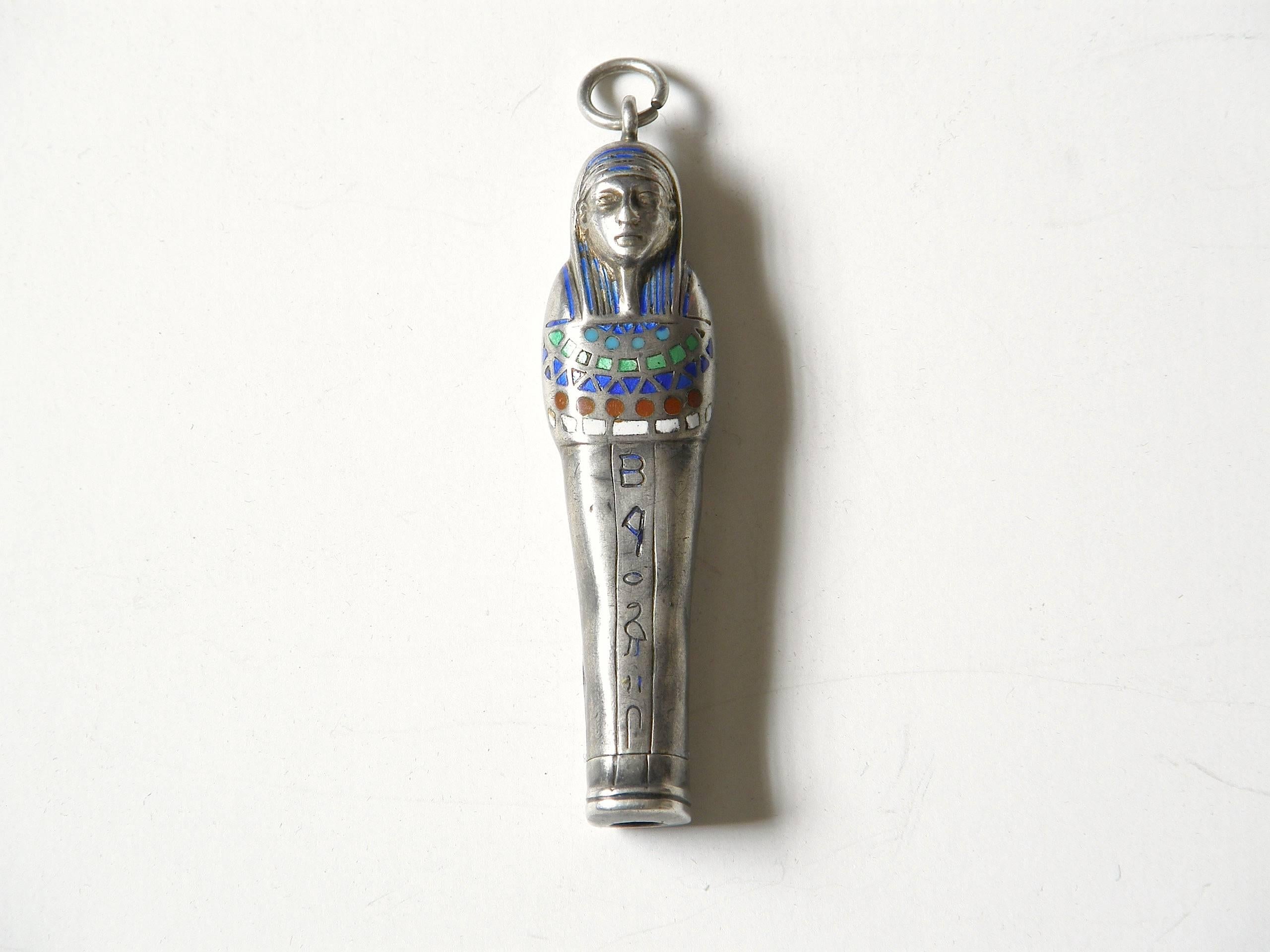 This mummy / sarcophagus shaped pendant has a retractable pencil inside. It's the kind of mechanical pencil that was often carried as a necklace or chatelain and used for filling out dance cards. This c. 1920s,  Egyptian Revival example is made of