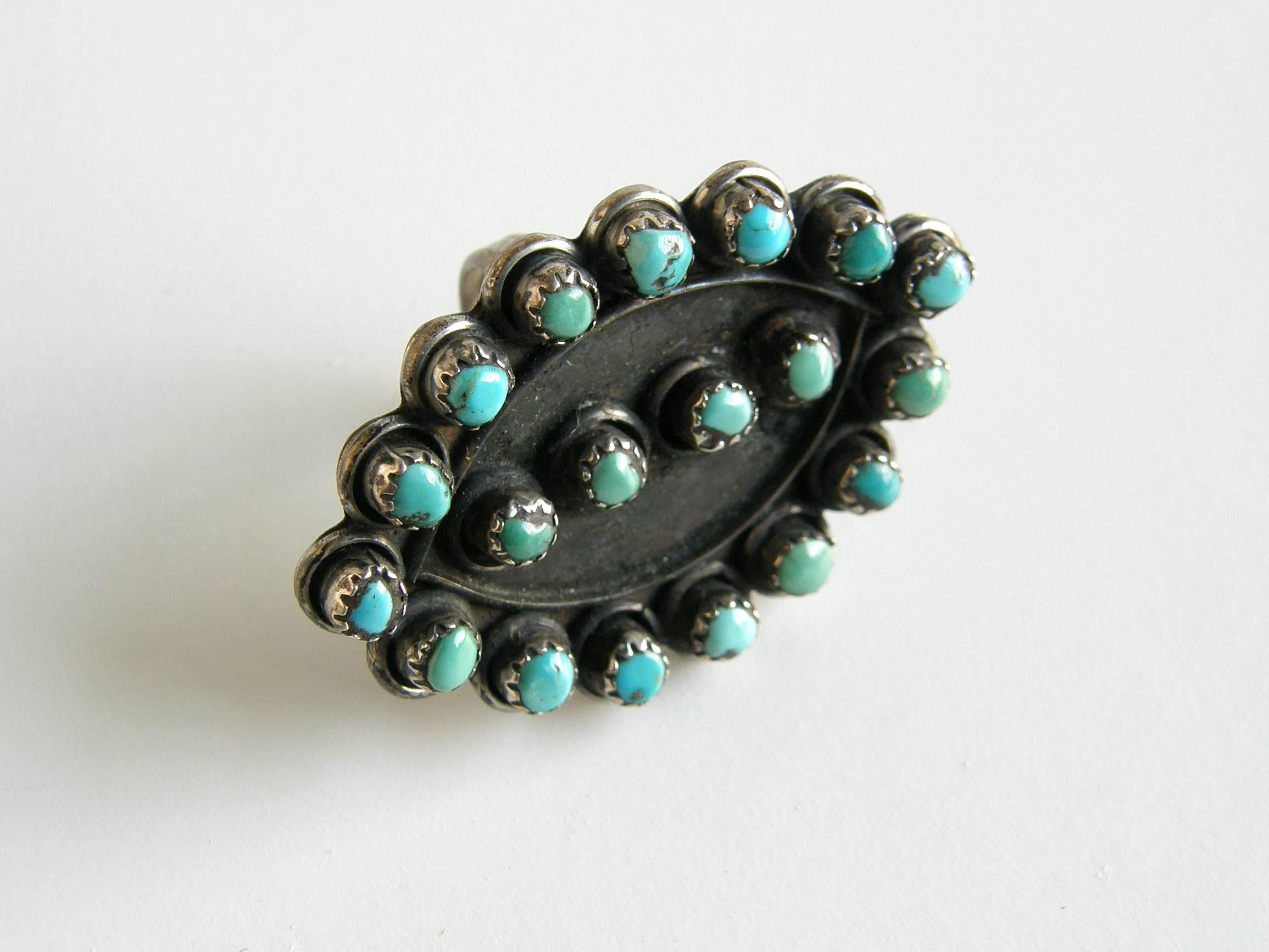 Large scale sterling and turquoise petit point style ring, c. 1920s or 1930s. The face of the ring is eye shaped with small, round, bezel set turquoise dotting the edge and forming a line down the center. The silver background has a lovely, dark