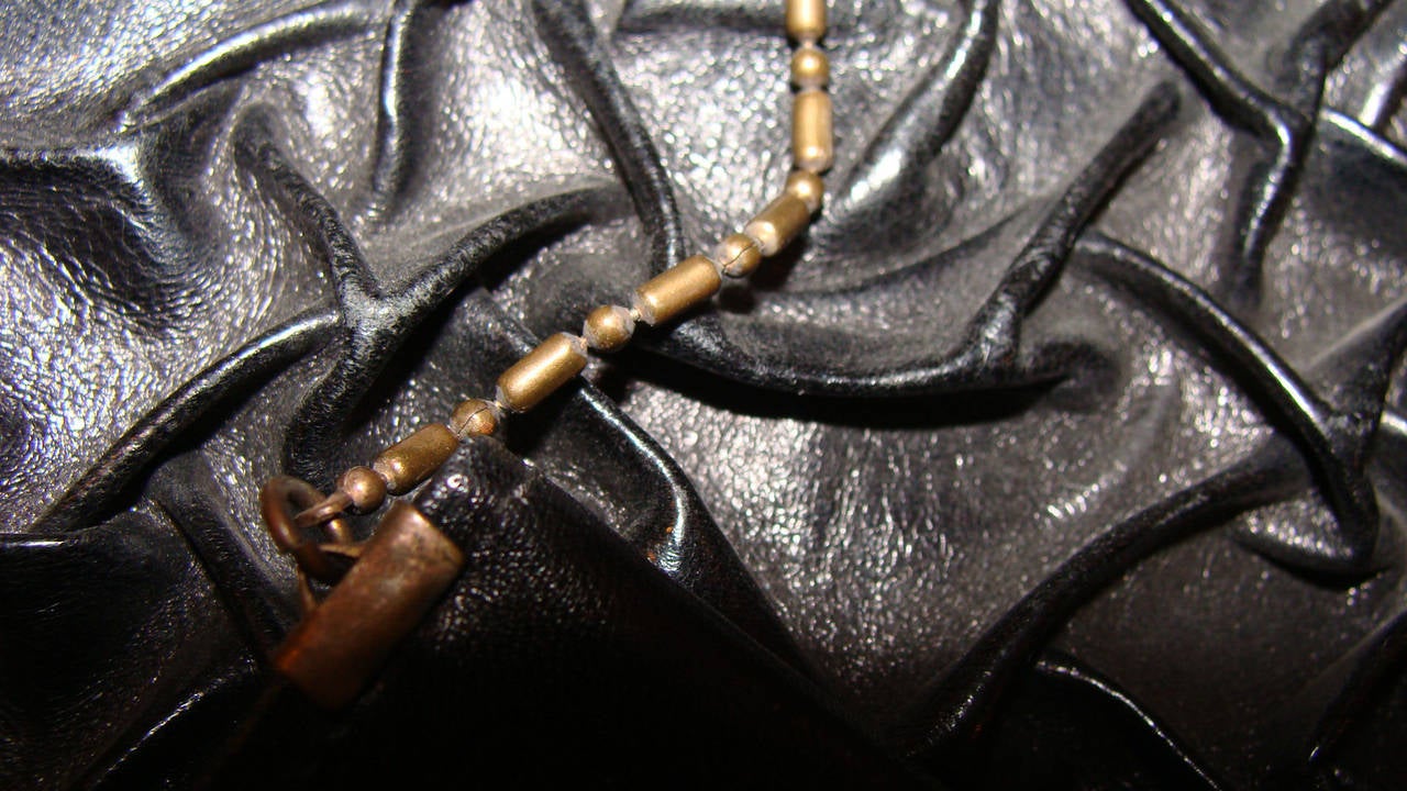 This is a most unusual evening bag.  It is made of black leather and has a type of abstract ruching.  The pattern is not sewn and we are not sure of the technique used to create this abstract effect.  The metal frame is brass and is heavily textured