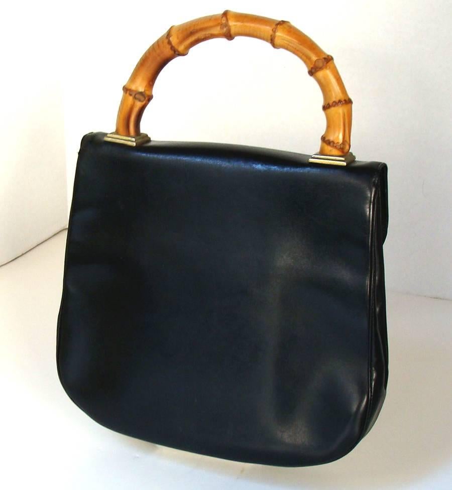 This is the first time we have seen this example (and we have been looking since the 70's).  This black box calf bag is spectacular .  We have no idea who designed it, nor do we know who made it.  The front tucks, the piping, the drop bamboo clasp