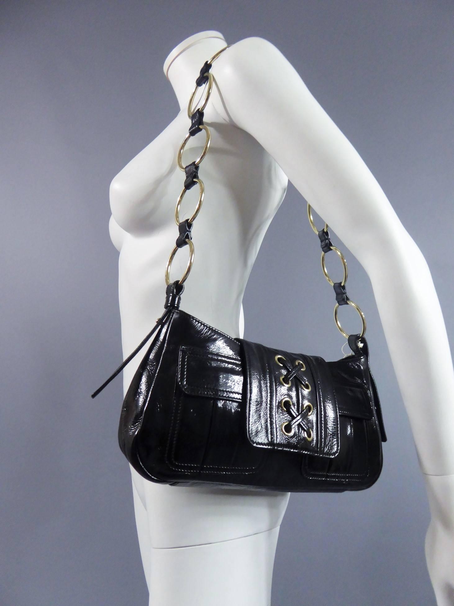 Circa 1980

France

Yves Saint Laurent Rive Gauche bag in black vinyl. Rectangular format. Opening with flap and metallic insivisible golden clip. Flap closure inspired by the iconic Saharan jacket of the couturier with eight rivets of gold metal