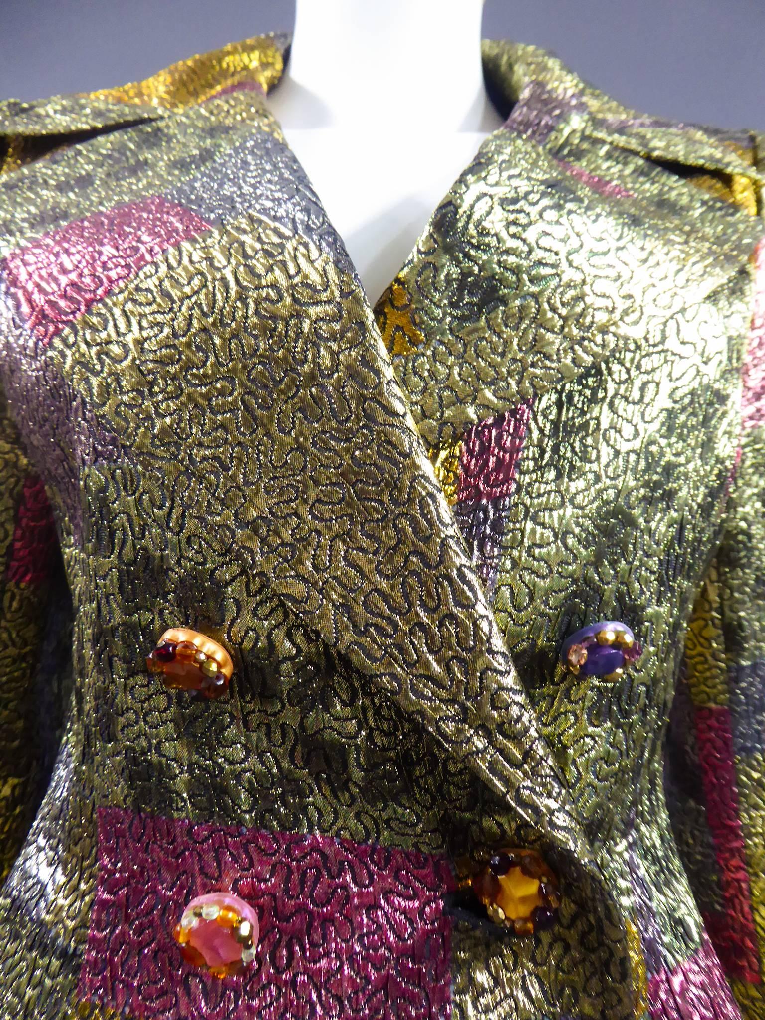 Circa 1980

France

Christian Lacroix skirt suit. Multicolored lurex with pink, purple, yellow, mimicking leopard skin in green, silver blue squares and rectangles. Creates the illusion of a disorganised checkered pattern. Black thread embroidered
