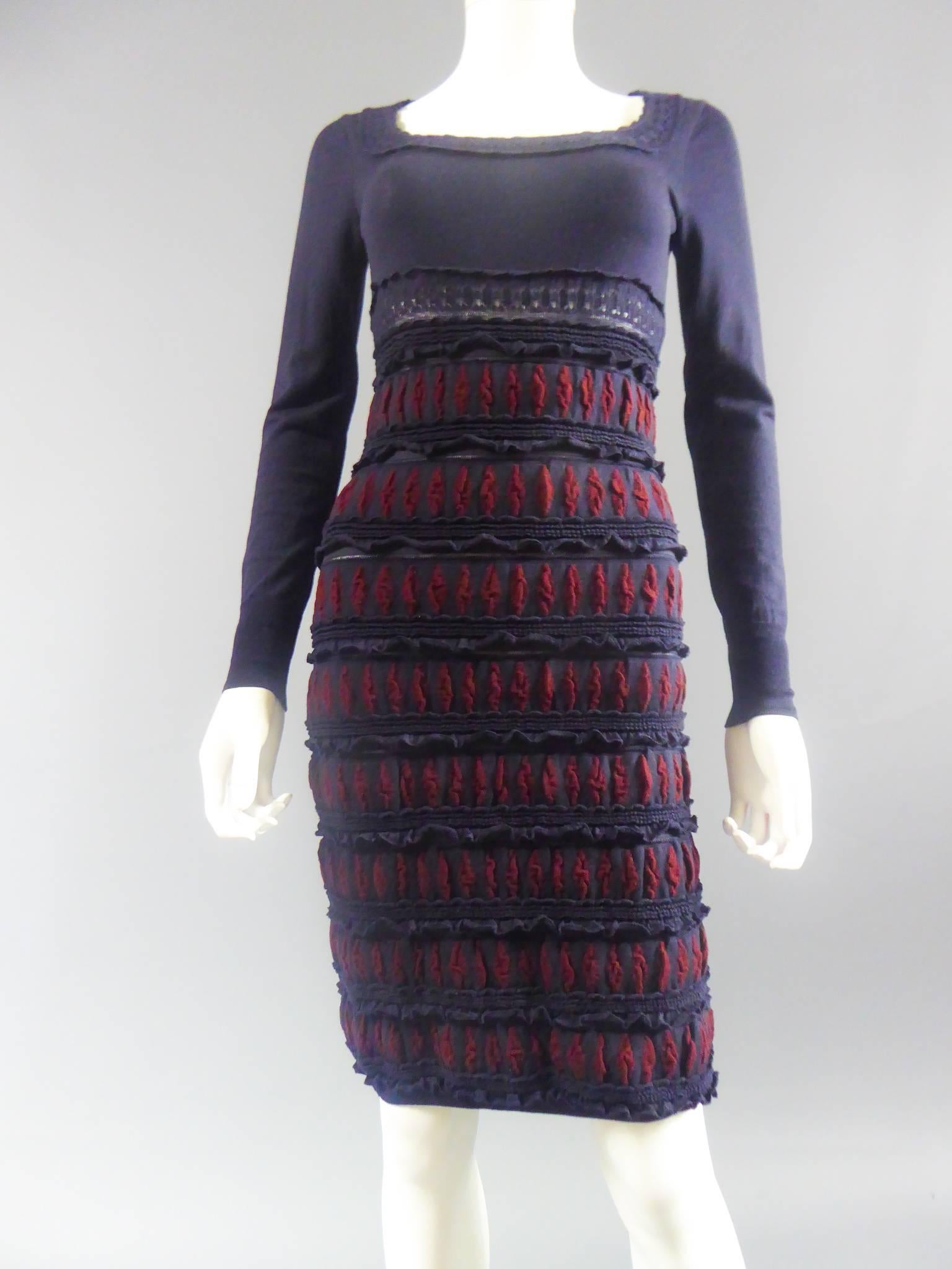 Circa 2000

France

Azzedine Alaïa long-sleeved dress and midi skirt in navy blue and red wool. Detail of wool lace on the collar, under the chest. Dress skirt alternating openworks, ruffles and oval patterns on navy blue stripes background. The