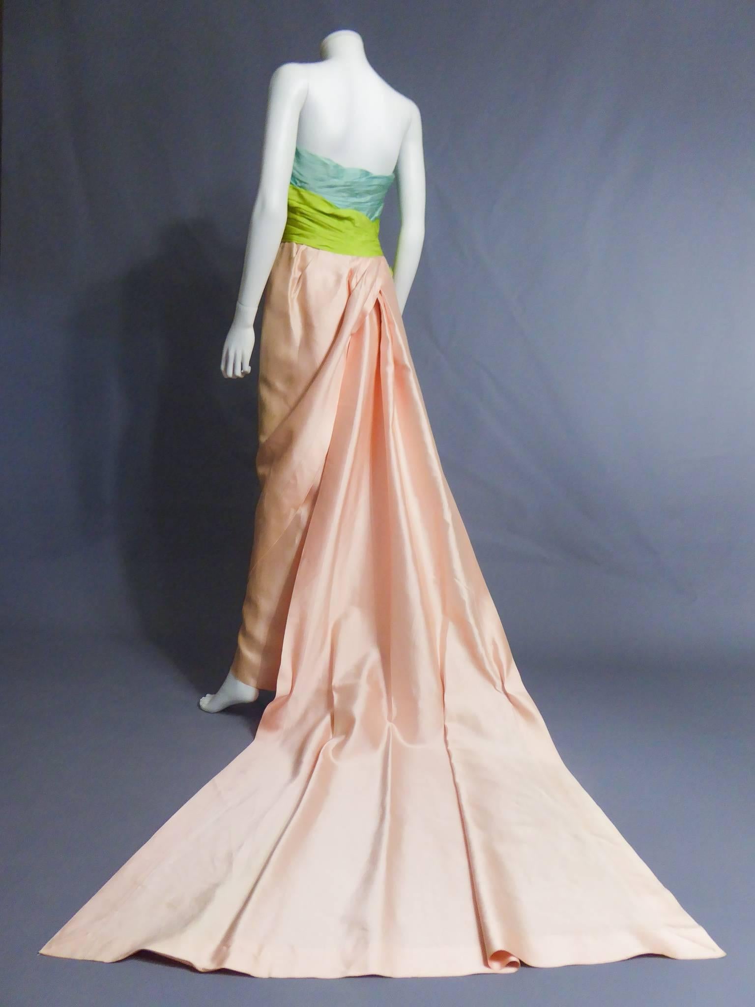 Circa 1990

Paris, France

Strapless Haute Couture evening gown with long satin train. Bustier draped with a millefeuille of blue and green silk taffetas, closing with snaps fasteners. Long sewn twill silk tube skirt with an opening over the ankles