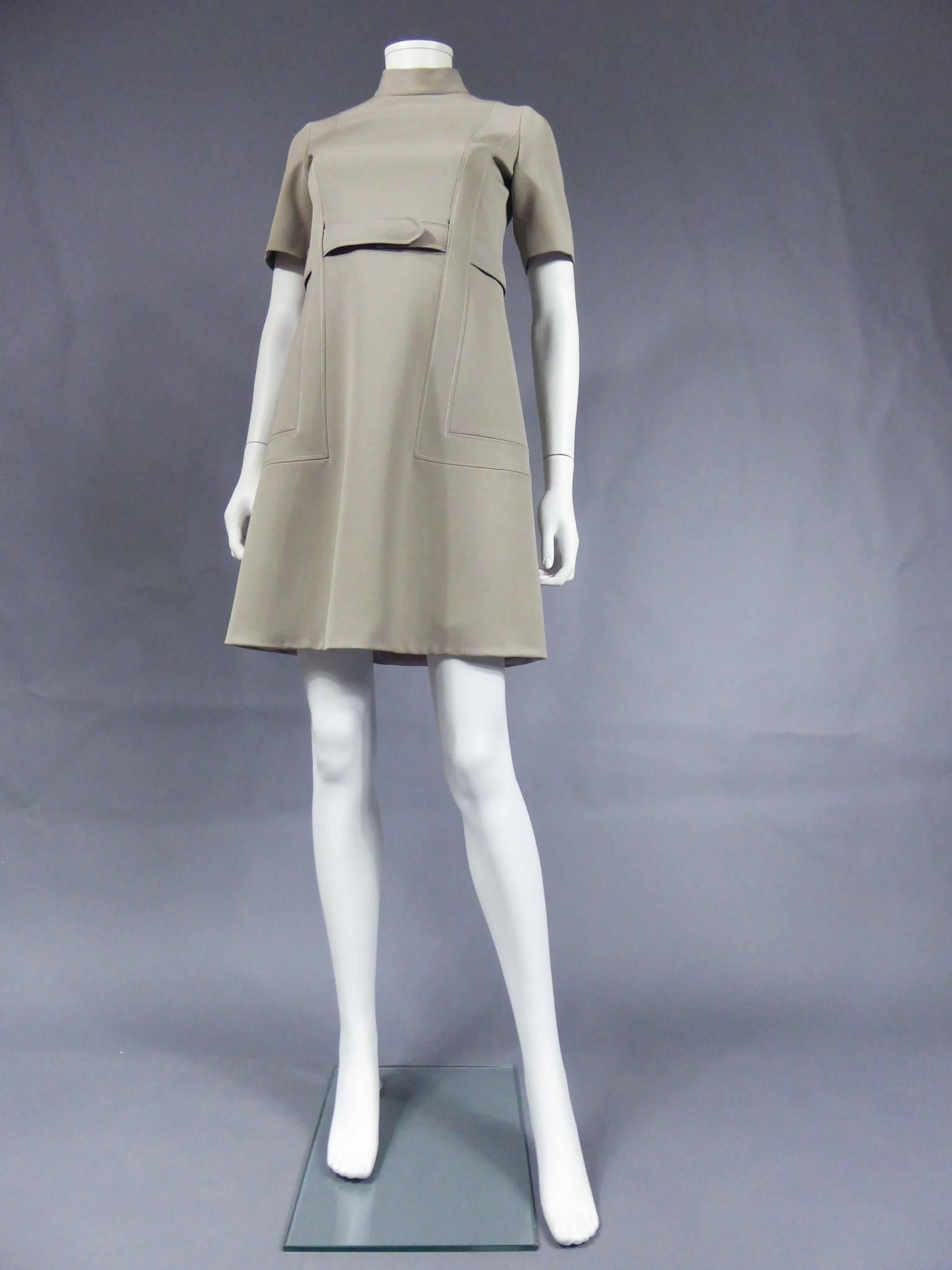 Circa 1968

France

Ted Lapidus by Olivier Lapidus ensemble in mastic color consisting of a dress and a coat. Dress with short sleeves and small collar. Powder pink lining in nylon. Belt closed by two snap buttons couture finishes. Graphic seam on