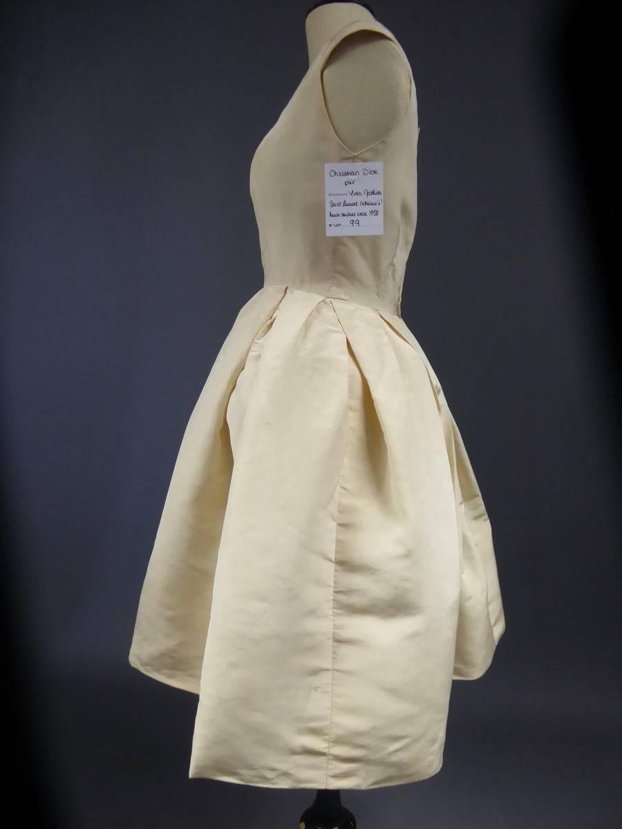 Circa 1958/1960 
France Haute Couture

Attributed to Christian Dior by Yves Mathieu Saint Laurent cocktail dress and dating from the period 1958/1960. Cream silk reps with boat neckline, sleeveless, fitted large pleated short skirt. Silk organza
