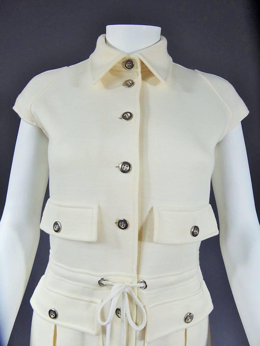 CIRCA 1970 -1975
Frankreich

Haute Couture Kleid von Andre Courrèges mit der Nummer 22057 aus den 70er Jahren. Dickes cremefarbenes Trikot (70% Acryl 30% Wolle) und  große Nähte, passendes Nylonfutter. Redingote gerades Kleid mit elf silbernen
