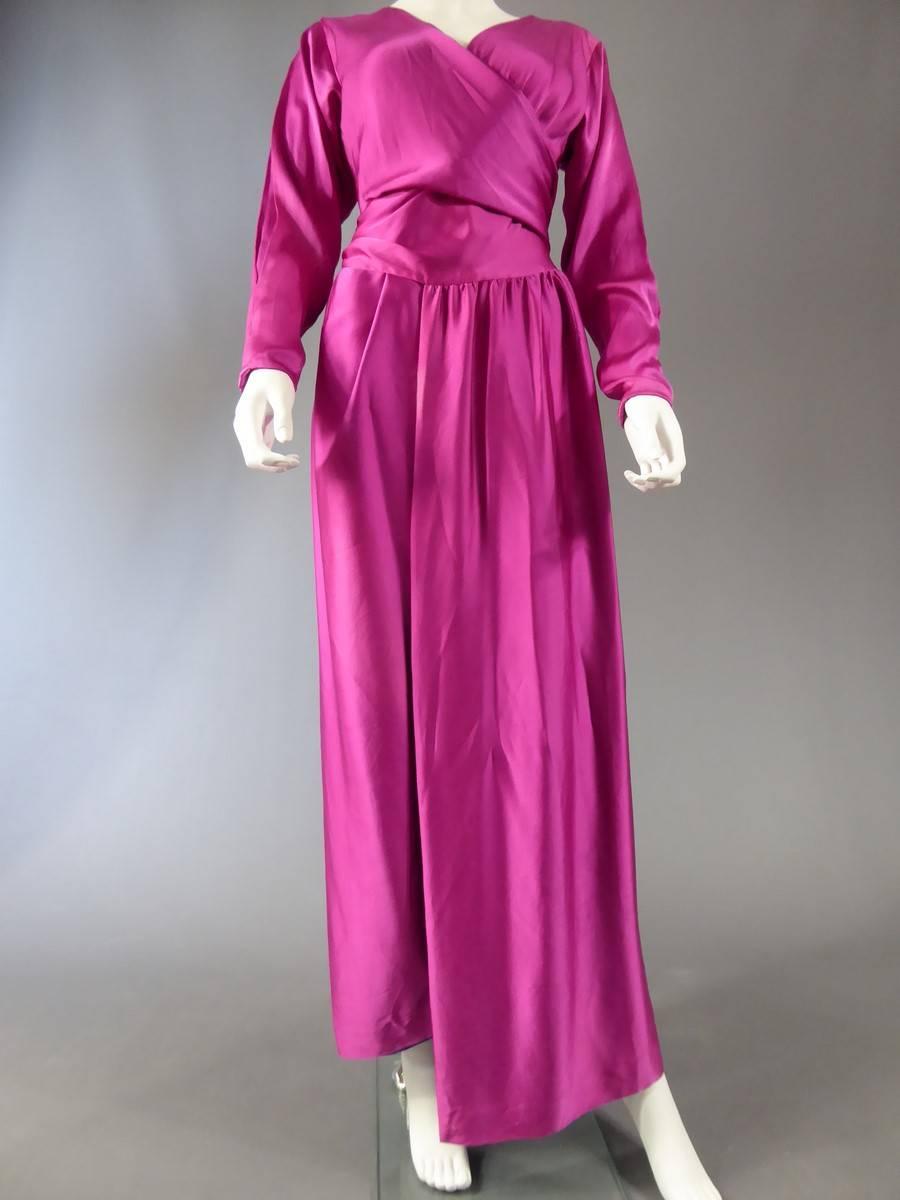 Circa 1990

France

Long evening dress Jeanne Lanvin Numbered 18073. Fuchsia brilliant satin silk 100%. Fully lined with a purple and cream silk dyed by hand closes with a knot in the back with the help of a small size passes .. Very fluid dress can