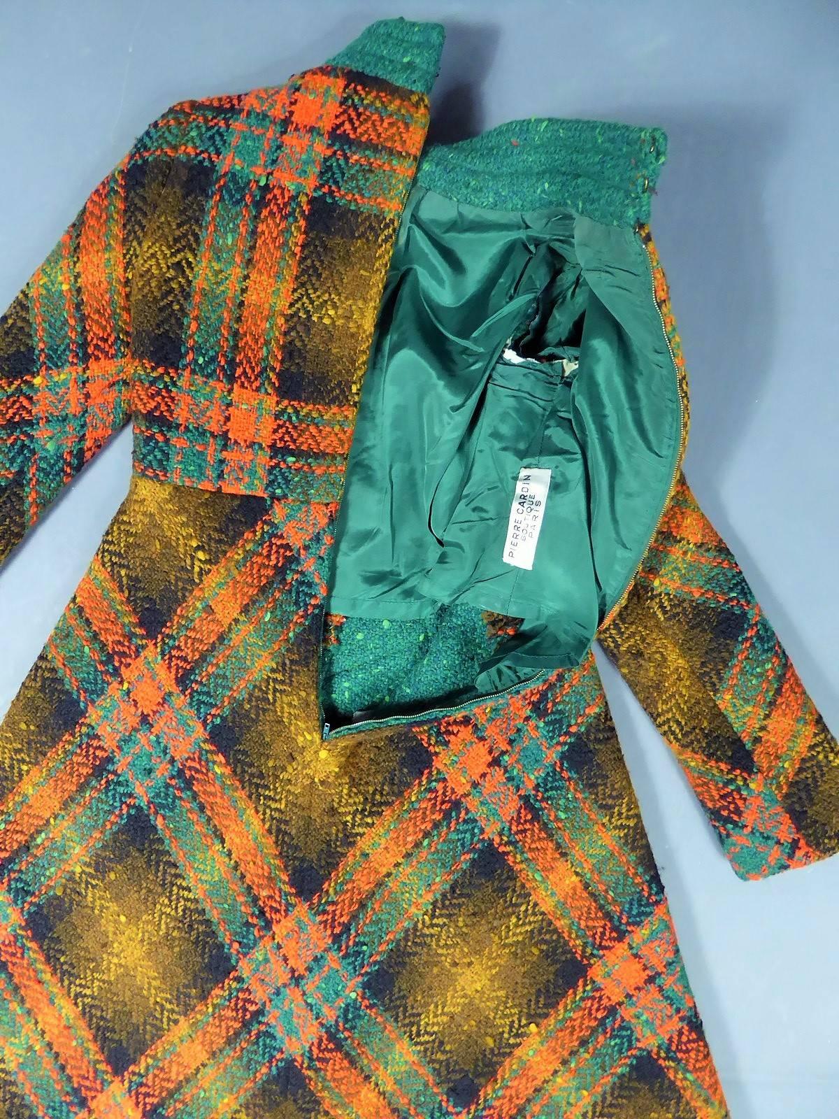 Autumn Winter 1970/1971

France

A historical model, a Maxi Chasuble Dress in thick tartan by Pierre Cardin Boutique. Slightly stretchy weave in large woolen knits with green, duck blue, ochre, brown and orange checks. Green bib with large bakelite