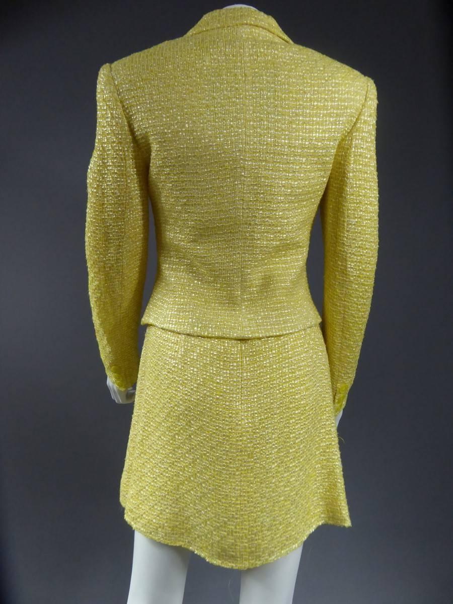 Circa 1990

Italie

Robe tailleur Couture jaune de Versace Jeans (fabricant de produits de mode italienne ) en soie et coton , composée d'une robe et d'une veste jaune assortie .

Robe à boutons nacrés avec bretelles et décolleté rond se ferme dans