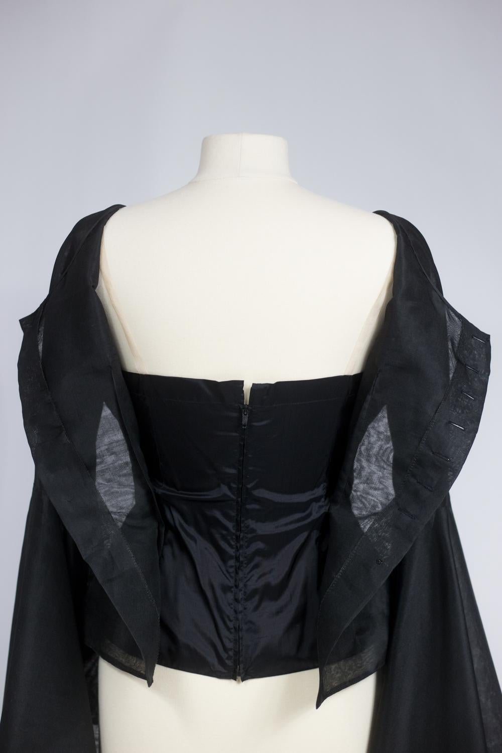 Circa 1970/1980
Francia
Splendida blusa in organza nera di Pierre Cardin (attribuita a) risalente agli anni '70/'80. Camicetta con scollo a barchetta abbottonata sul davanti e maniche drammatiche che terminano in gigantesche pagode, tagliate in