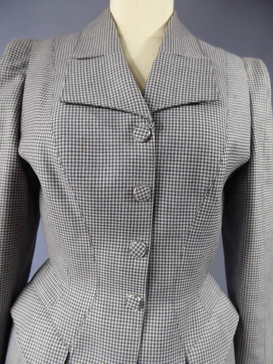 Superb skirt suit designed by French couturier Thierry Mugler. The suit is made of a jacket and a skirt with white and grey tiles making a pattern called Vichy in France. 
The jacket presents the typical cutting of the 1980s with wide