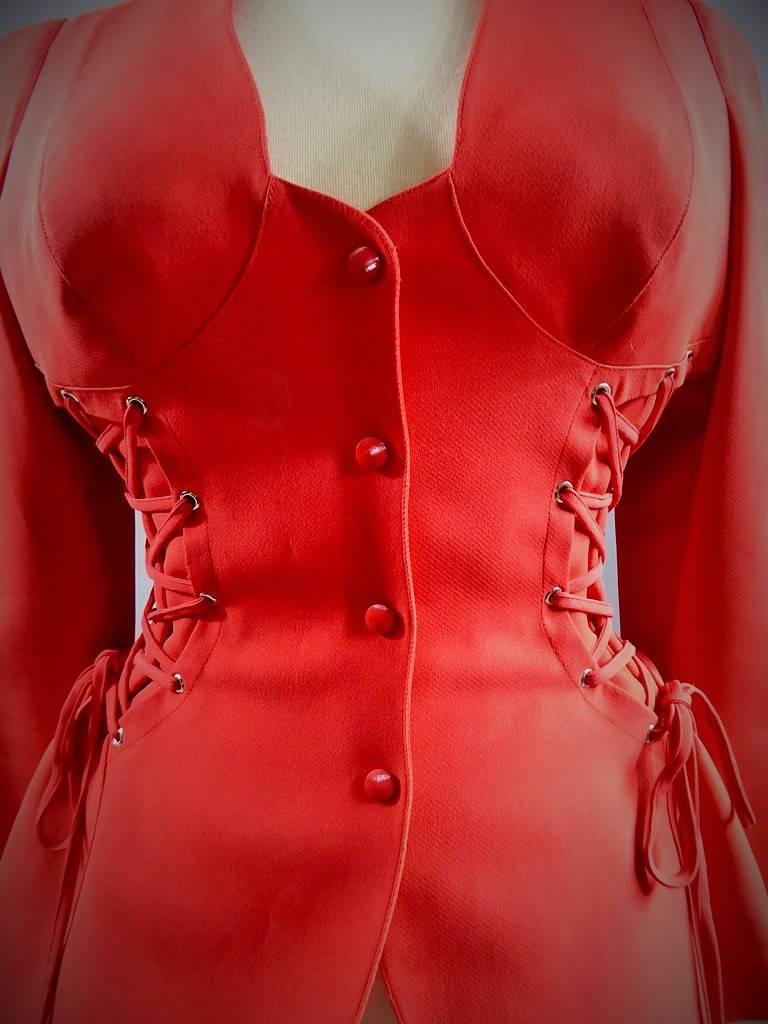 Circa 1980

France

Scarlet red bustier jacket in acetate by Thierry Mugler with lacing on the sides to tighten the waist. Laces ending in small metal tips. Epaulettes giving the vest a very structured appearance. Front closure with red press studs.