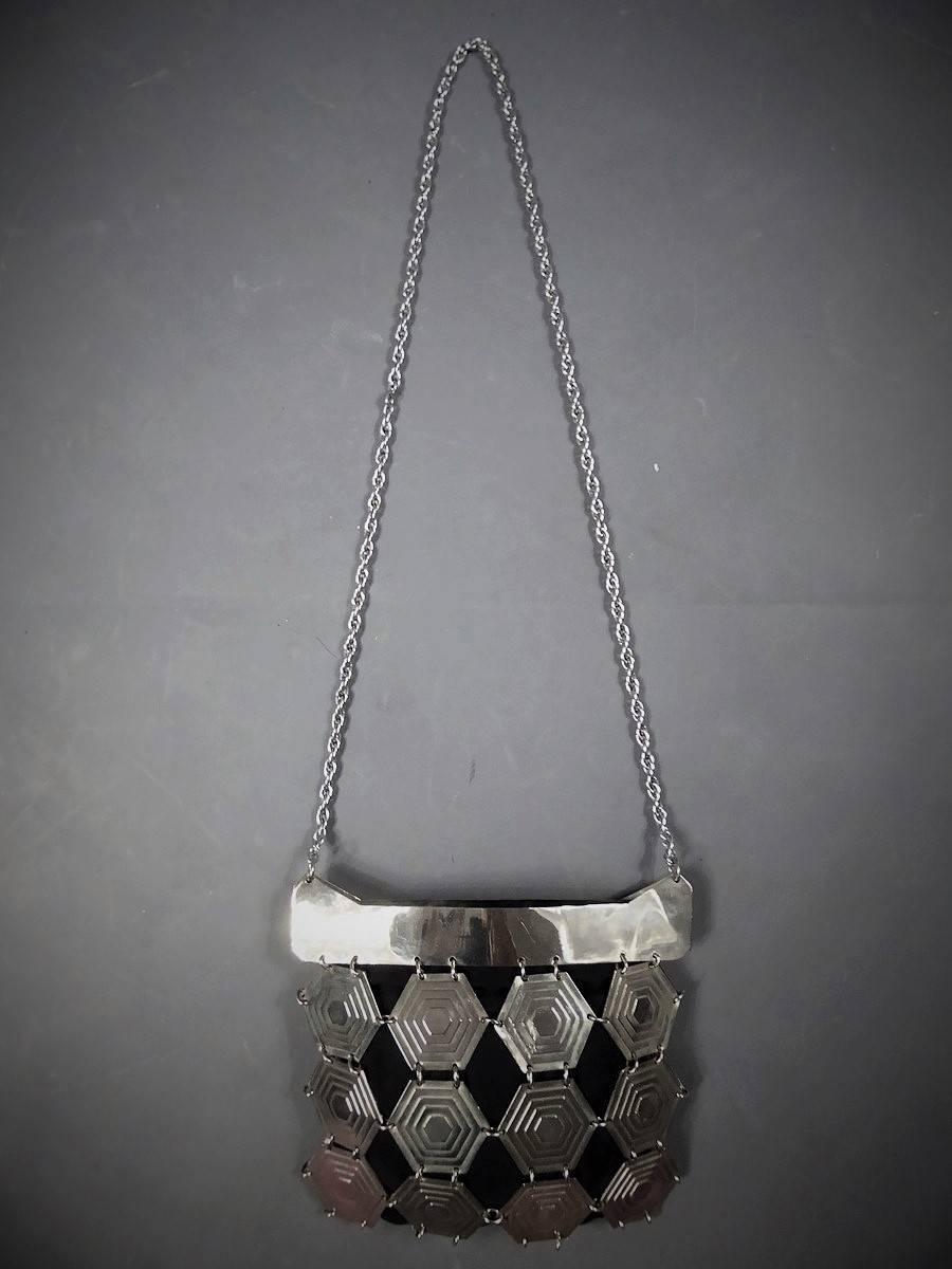 Circa 1980.

France.

Paco Rabanne bag in hexagonal metallic silver pieces on fluted black silk fabric. Emblematic of the work of the couturier who is akin to the creator of this period type Vasarelly. Long handle in fine silver metal links. Narrow