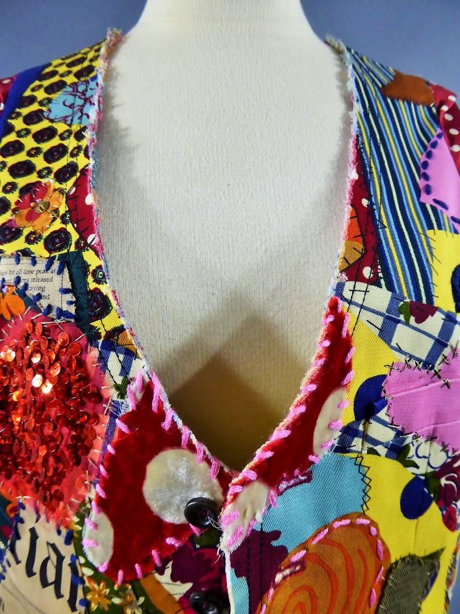 Circa 2001.

France.

Waistcoat vest, sleeveless, V-neck, by John Galliano. Multicolored patchwork pieces in 100% cotton but also in red sequins, and pieces of velvet stitched or embroidered with 100% polyester yarns of different colors (gold, navy