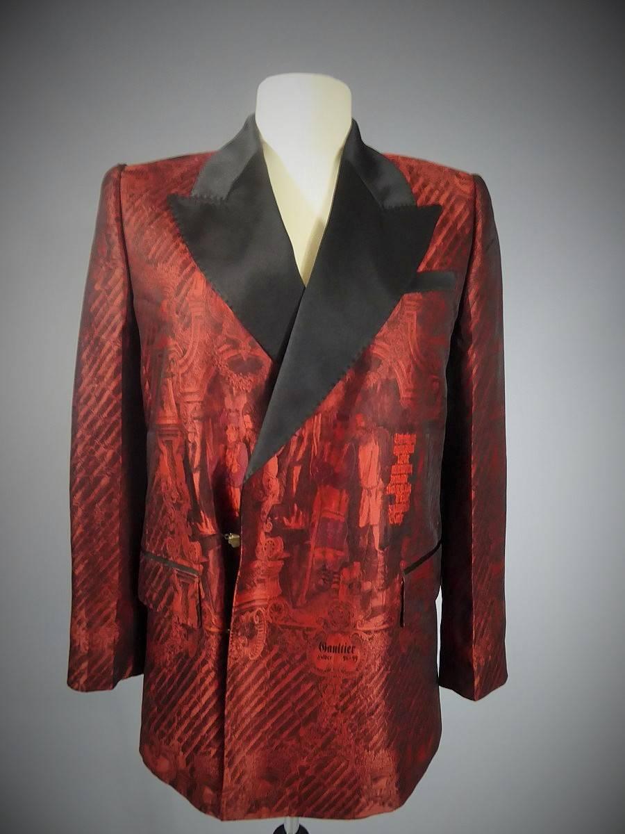 1998/1999

France

Jean Paul Gaultier tuxedo jacket and trouser from Winter 1998/1999. Woven on the front of the jacket. Tuxedo jacket in red and black damask satin representing scenes from mythology and baroque architecture. Fake pockets with