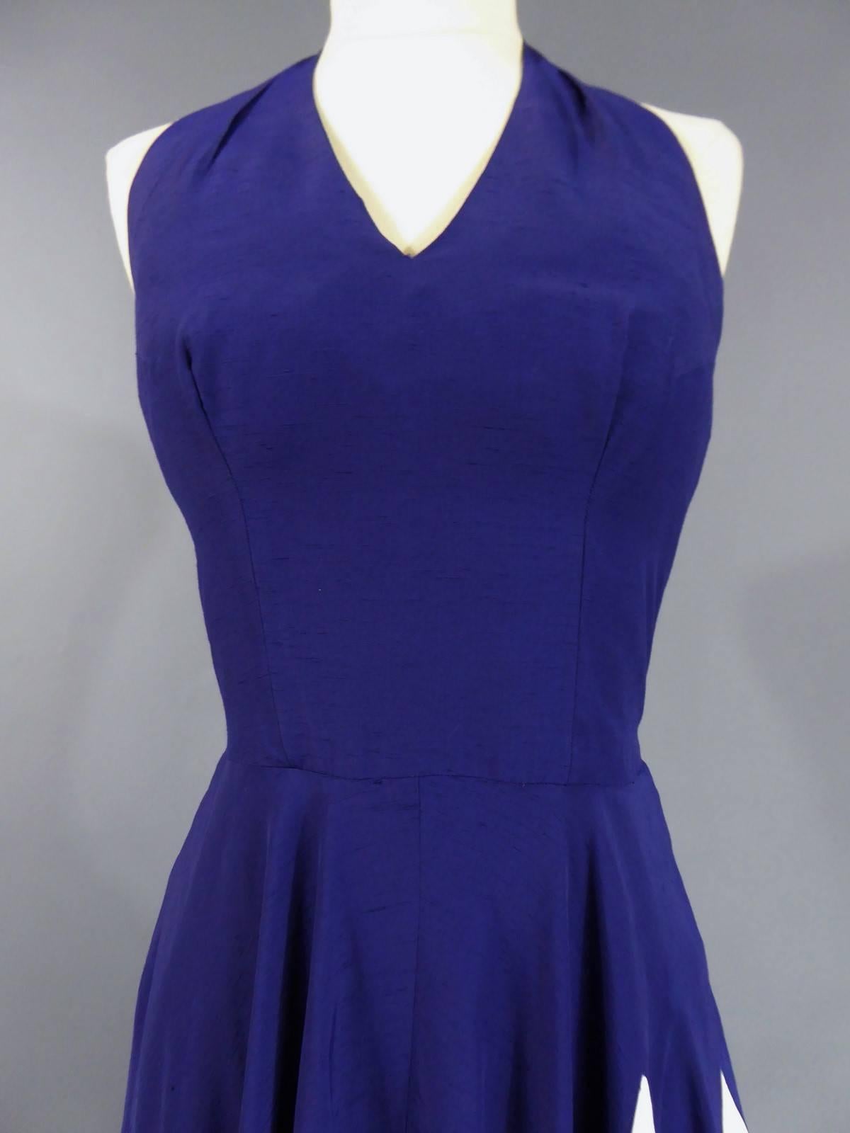 Circa 1950

Henry à la Pensée sapphire blue and white slubbed halter-neck dress from the 1950s. Blue points falling dramatically on the white skirt. Zip closure in the back. Natural silk. White tag with purple graphism saying Henry à la Pensée Made