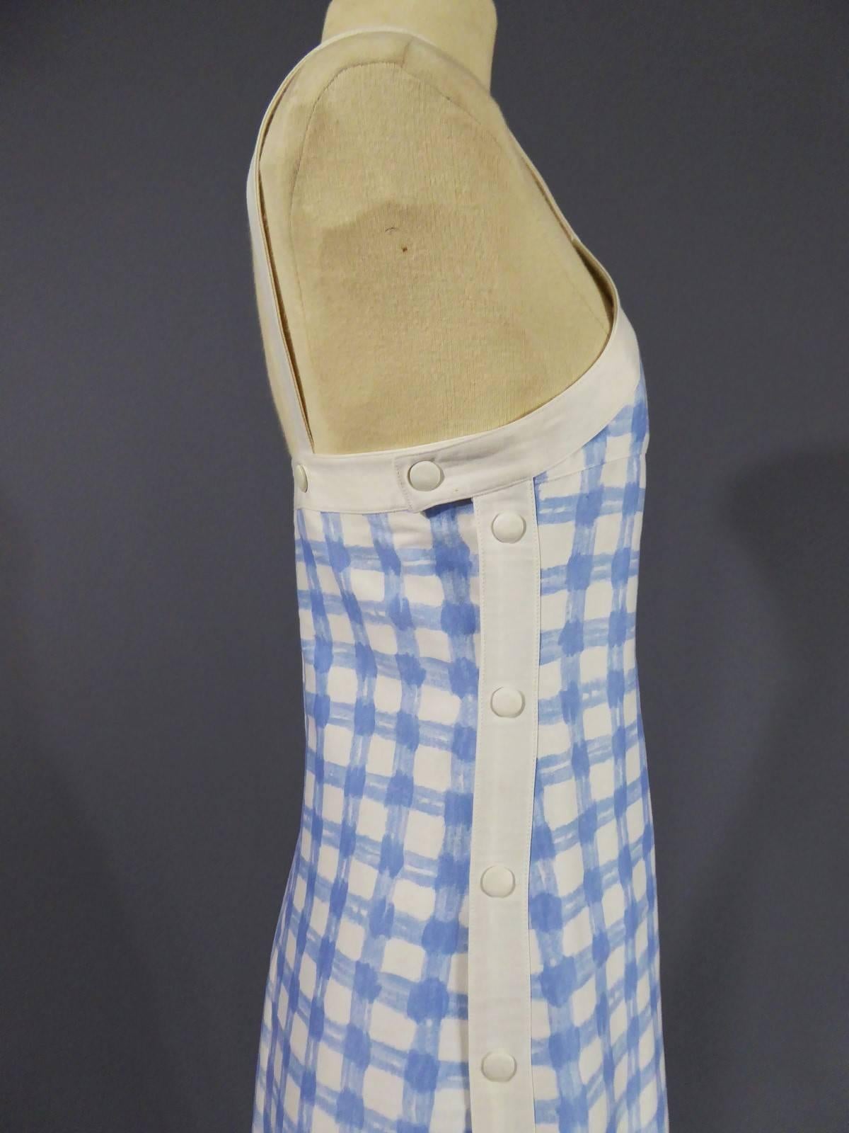Circa 1970

France.

A Long maxi dress from André Courrèges, Taty Inspiration. Closes with 15 snaps on each side of the dress. Straps closed by press studs in white. Cotton jersey printed in the style of painted Vichy blue pattern, gingham, on a