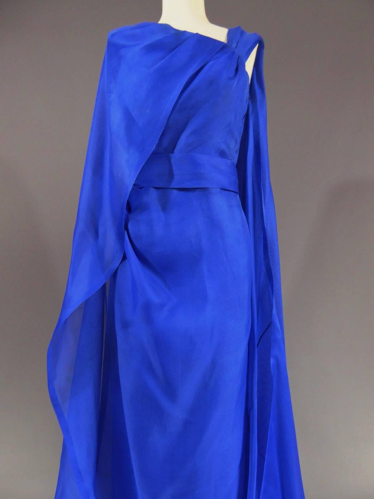 Circa 1980

France

Long evening dress Givenchy Haute Couture. Prototype workshop with bolduc n ° 97, Laura at Carmen. Magnificence of the drape reinforced by the presence of an integrated cape. Gazar light ultramarine blue. Integrated shoulder