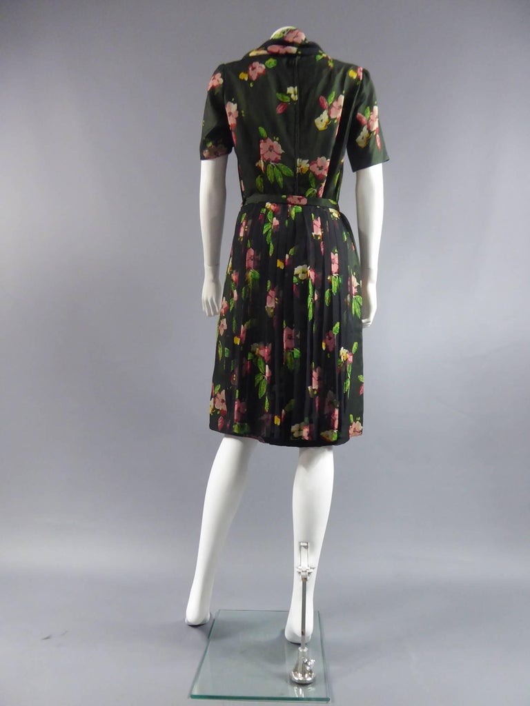 Circa 1950-1960

France

Unlabelled dress very good manufacturing, high-quality garment, chiffon flowers on green background. Short sleeves. Scarf neck can be tied. Fine pleated skirt, in the same fabric, coming to be added on the dress in the