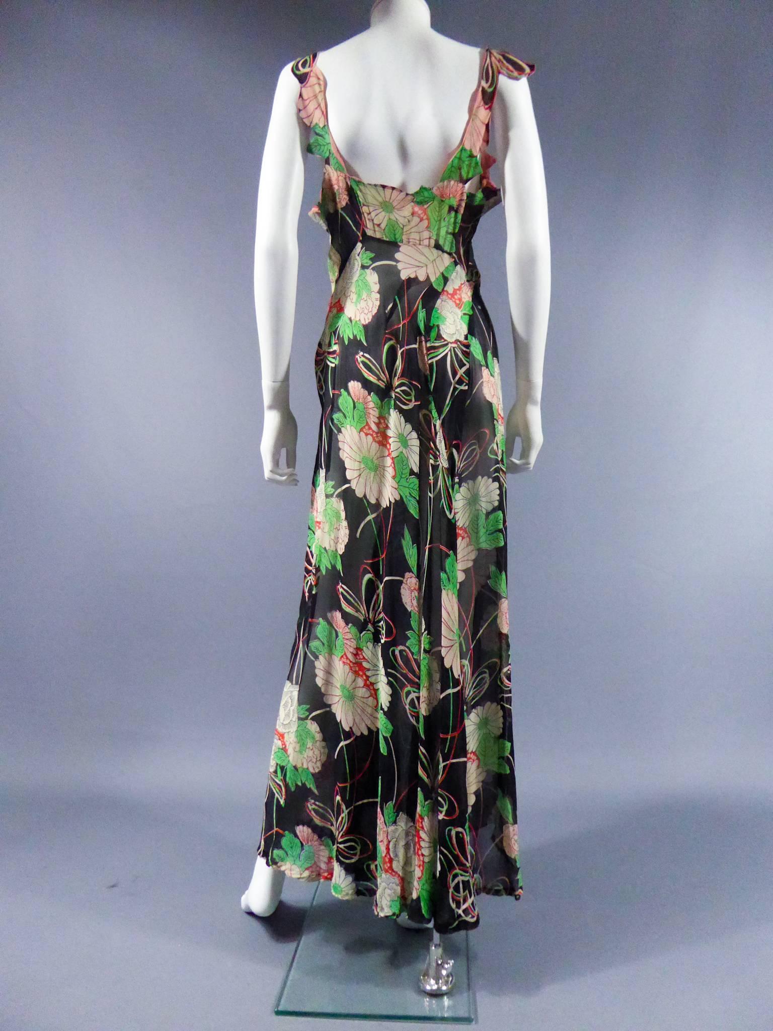 Circa 1930

England

Flowered printed dress with black background and pink flowers highlighted with red and green leaves. Details of cutouts according to the shape of the flowers on the bodice of the dress creating a flap opening. Slightly