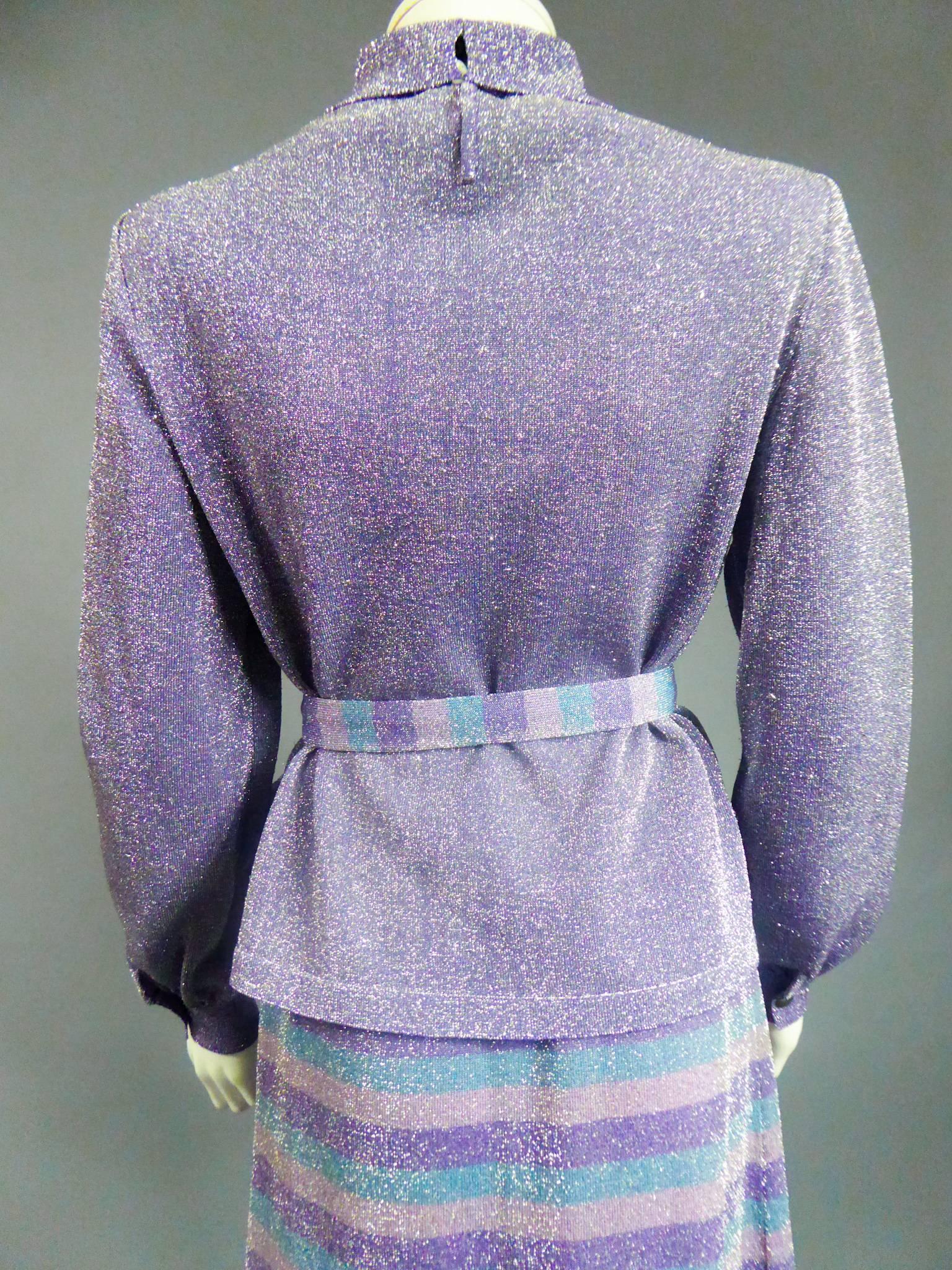 Circa 1980

France

Pierre Balmain three-piece knitwear set in silver and purple lurex. Long-sleeved, tight-fitting top with cuffs. Small turtleneck closing with invisible staples. Long flared skirt with elastic waist, petrol blue stripes, powder