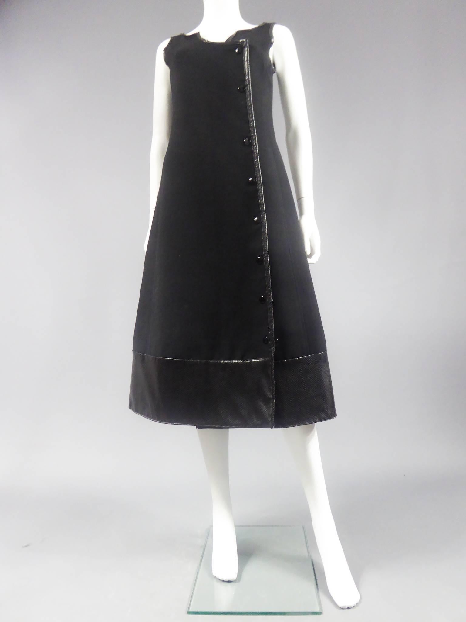 Circa 1970

France

Number 55540 Haute Couture wrap dress in thick black jersey with stitching and piping. Attaches by black snaps on the front, three are doubled to create the flare of the bottom of the skirt. Black skai band worked snake way and