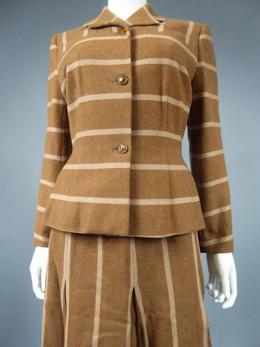 Circa 1950

England

Elegant skirt suit and Bar jacket in ochre and cream wool by the English brand HEBE sport between 1947 and 1952. BAR fitted jacket molding the hips and pockets above the chest ! Closing with three brown bakelite buttons. Note