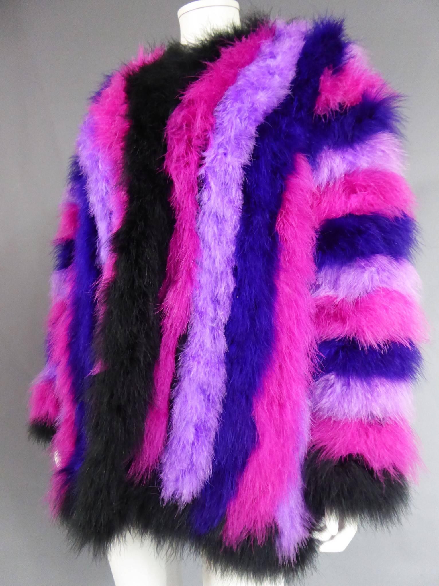 Circa 1980

France

Wide open long-sleeved coat in black ostrich feathers, fuschia pink, purple and purple. Vertical stripes on the front and back, horizontal stripes on the sleeves, creating a graphic effect of bright colors. Black satin lining.