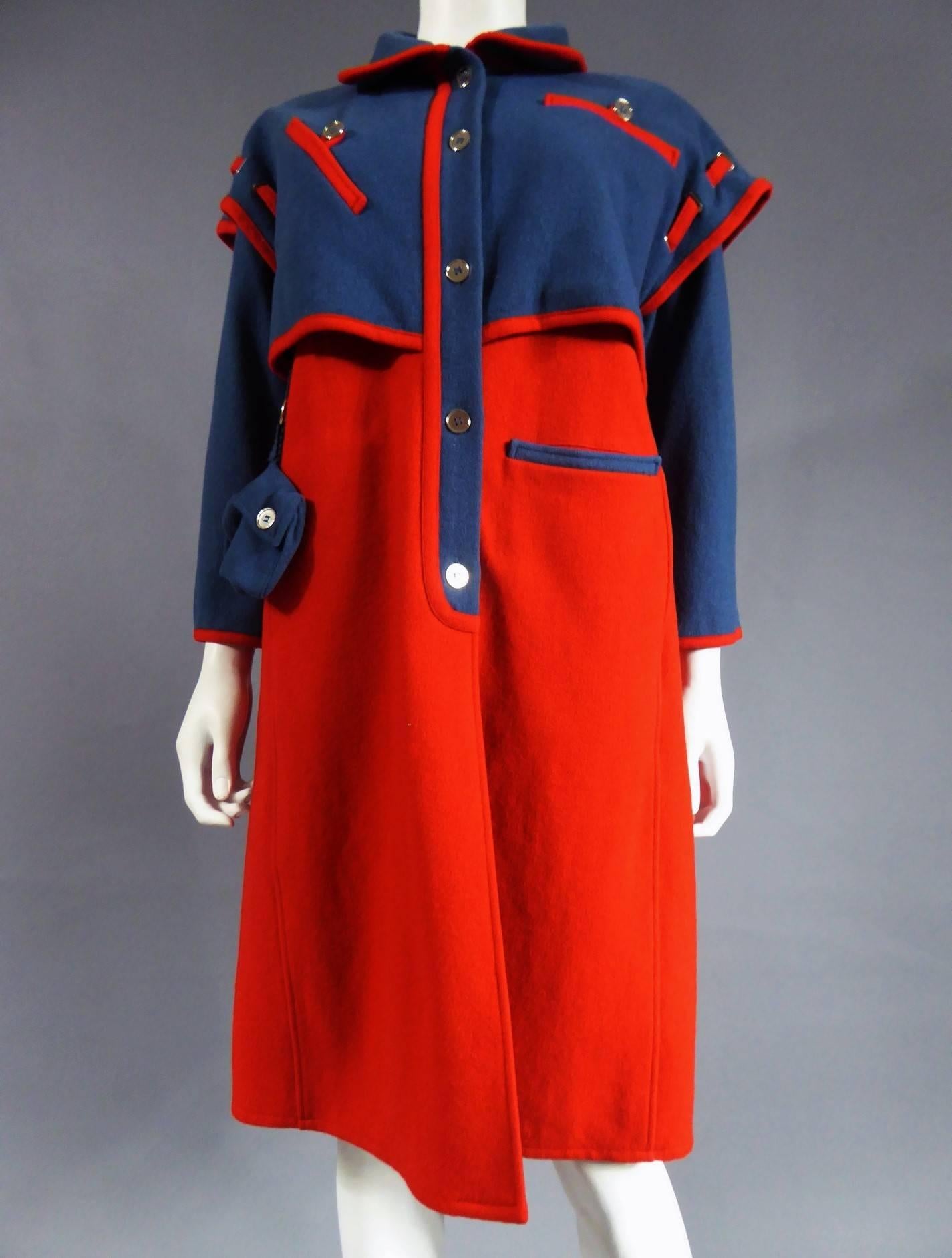 Circa 1968
France
André Courrèges coat in red wool with sleeves and short blue capeline with Claudine collar. Closed by five silver buttons. On the front of the capeline, two pockets with red opening and closing each by a button : on the left chest