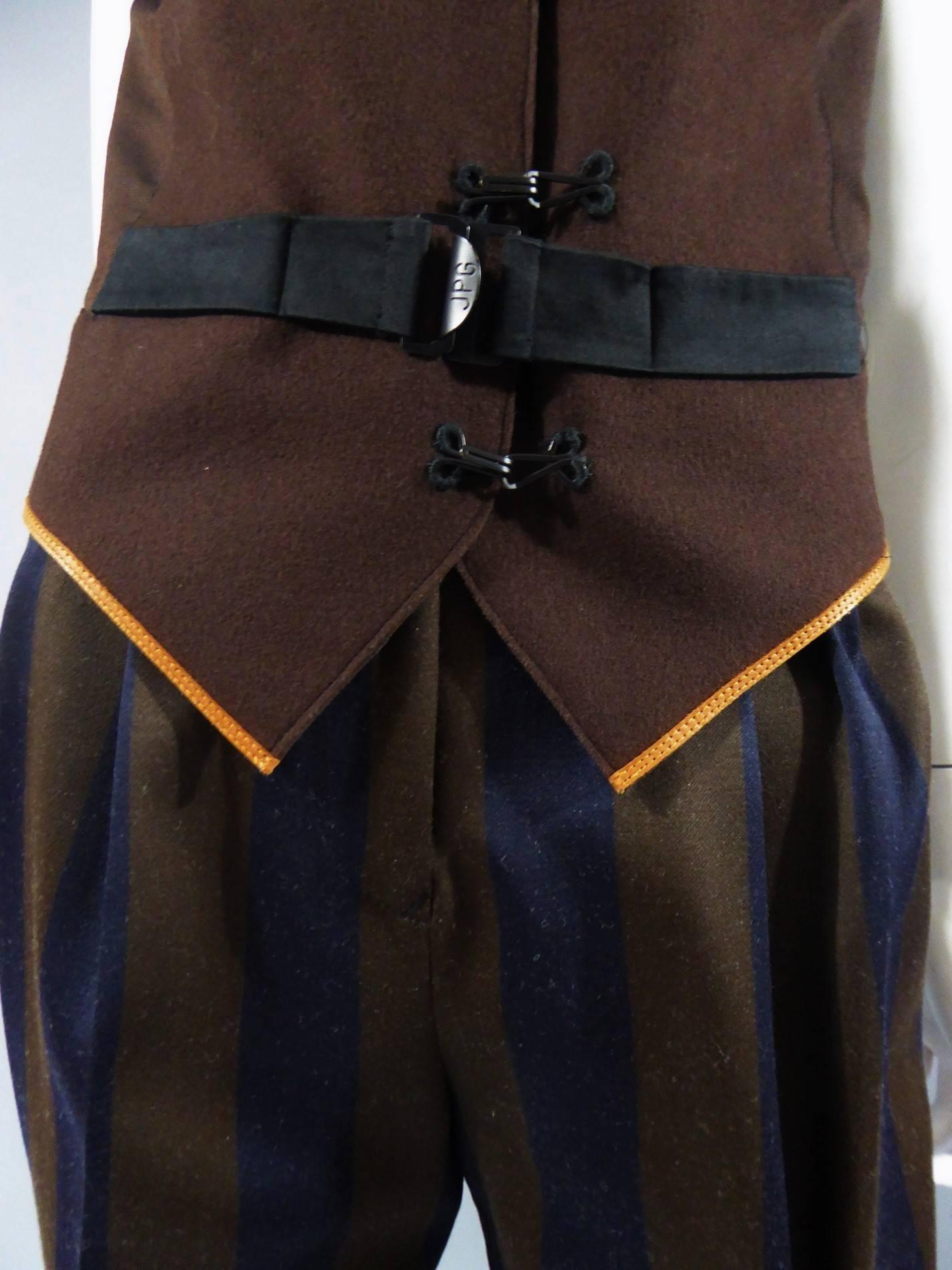 Etwa 1990/2000

Frankreich

Zweiteiliger Anzug aus Wolle Jean Paul Gaultier Woman. Ärmellose Weste mit ockergelbem Lederbesatz in der Taille. Schließt mit schwarzen Krallen auf der Vorderseite und einem halben Gürtel an der Taille, schwarz, dessen