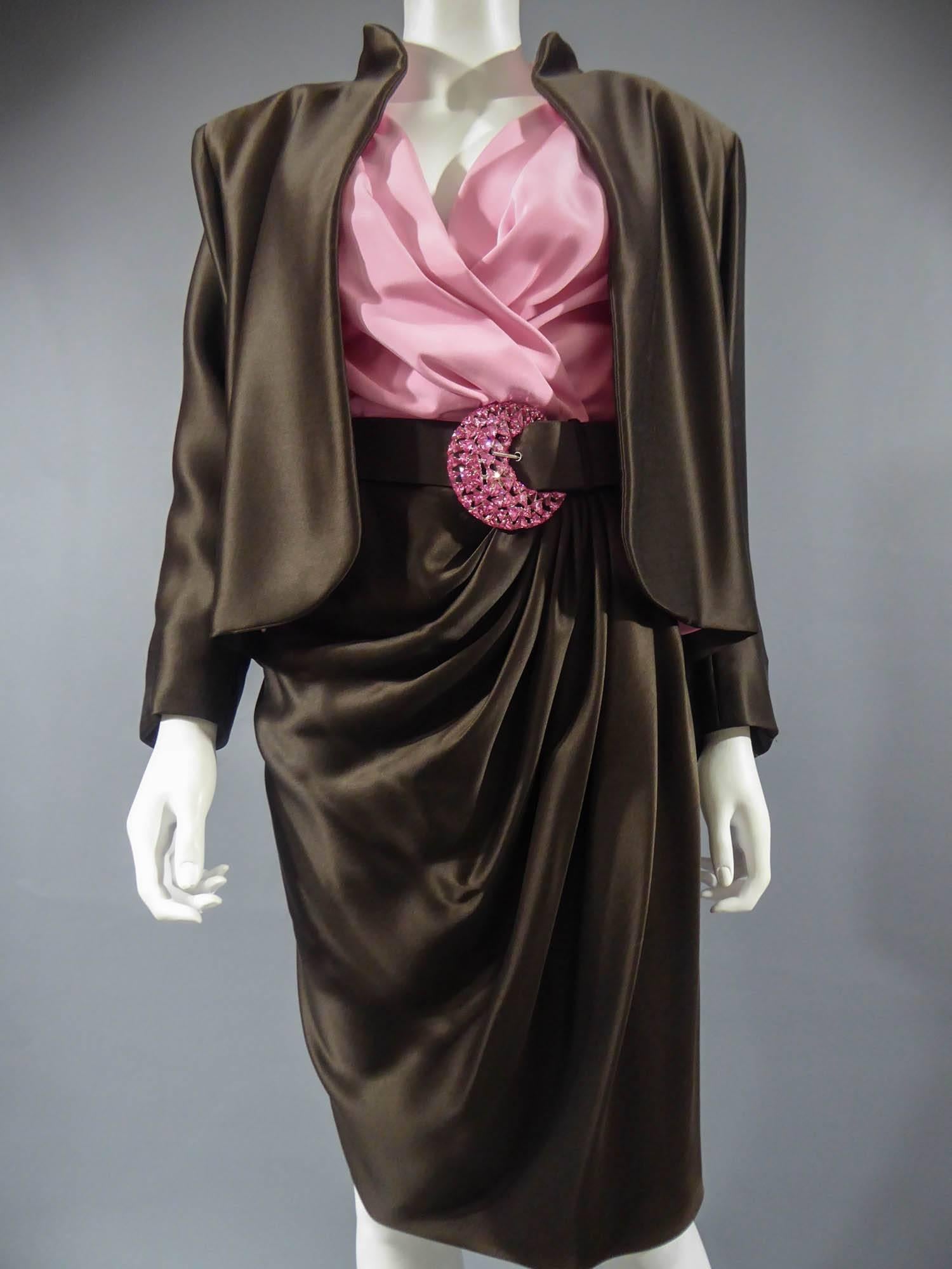 Um 1989

Frankreich Haute Couture

Luxuriöse Abendgarderobe, Haute Couture-Rock, Bluse, Jacke und   gürtel mit der Nummer 65123 aus der Kollektion Yves Saint Laurent 1989. Die tief ausgeschnittene Bluse mit breiten Schulterpolstern aus rosafarbenem