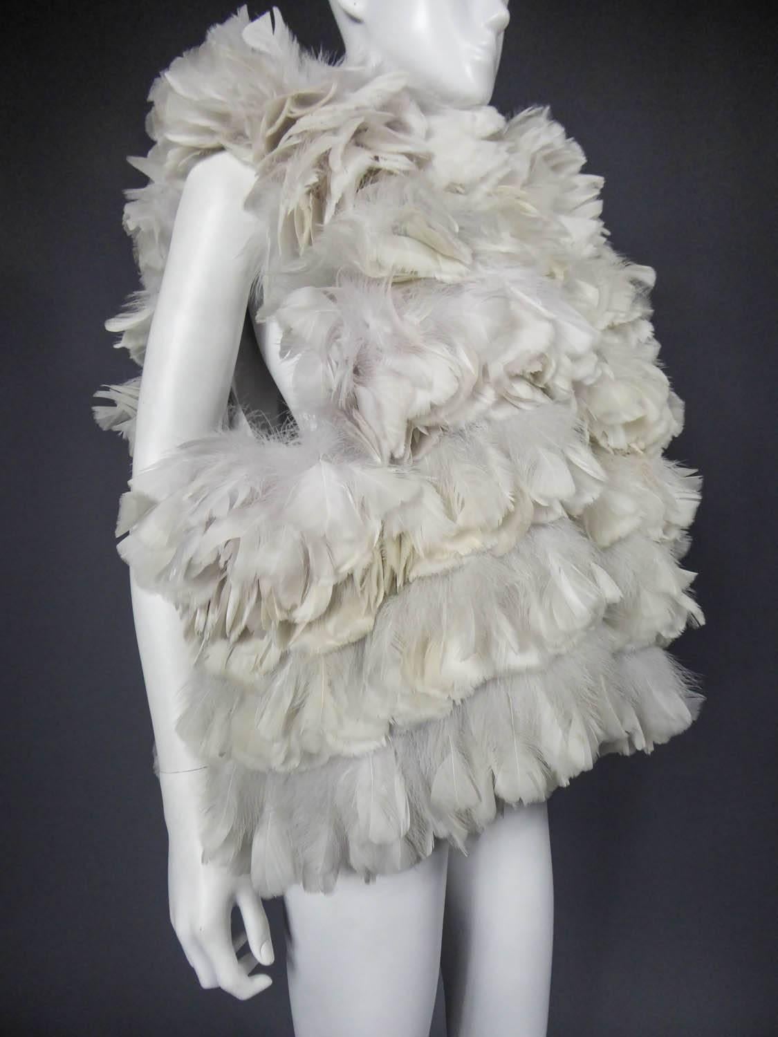 Circa 2000

France

Sleeveless jacket Sonia Rykiel in feather with a ball effect from the 2000s. Rows of feathers and downs from a wide collar in hen. Feathers in shades of gray ranging from white to straw yellow. Lining in pale gray silk taffeta.