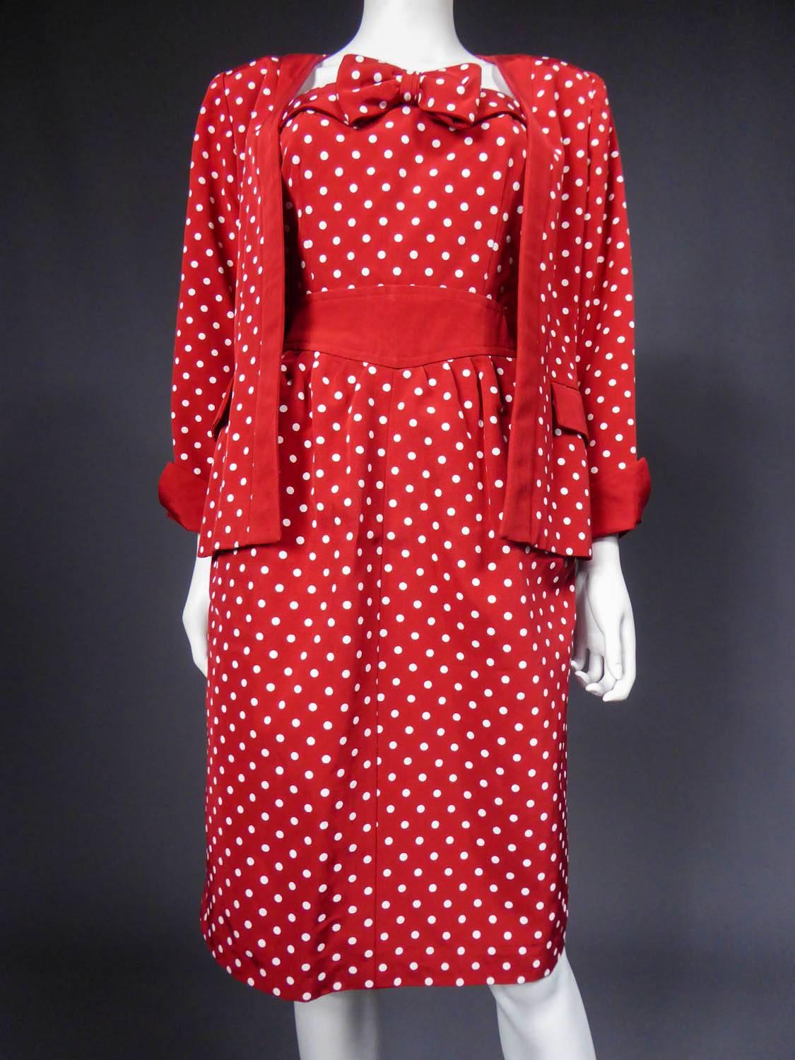 Circa 1980

France

Dress and jacket set Nina Ricci from the 80s in red cotton ottoman printed with white dots. Sheath dress with 2 pockets in bias on the hips. Bustier with lapels and large bow on the chest. Jacket with lapel effects on the sleeves