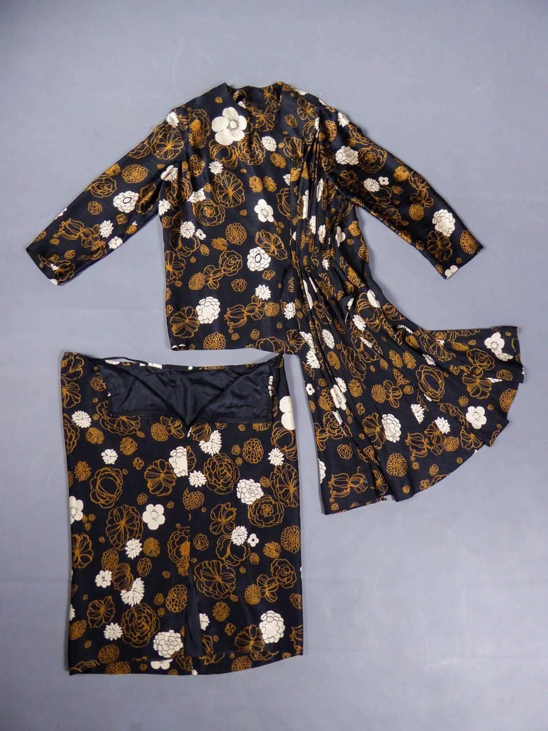 Circa 1980

France

Shirt skirt set Madame Grès Haute Couture from the 80s. Black silk satin with a matte and shiny effect, printed with light brown and white flowers. Asymmetrical pleated effect with small train on the hips. Blouse with long