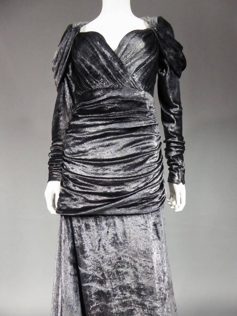 Collection 1982

France

An evening Couture dress from the 1982 Yves Saint LaurentFall Collection. Slashed train dress with anthracite gray velvet and silver lurex. Bust and hips finely pleated. Draped effect on the shoulders and back. Label Yves