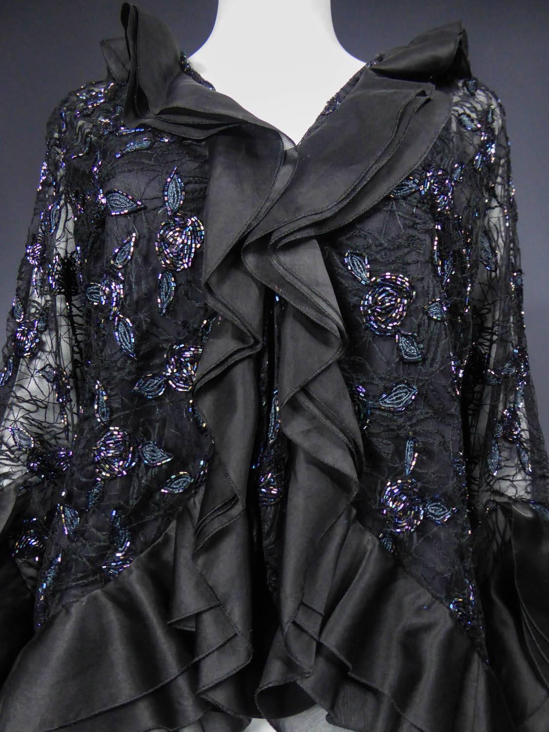 Circa 1980 - 1990

Japan

Jacket and tank top Hanae Mori Haute Couture from the 80's / 90's. Jacket in black tulle embroidered with blue and gray iridescent tubular sequins. Patterns of stylized flowers of art-deco type. ¾ Sleeves with 3 ruffles of