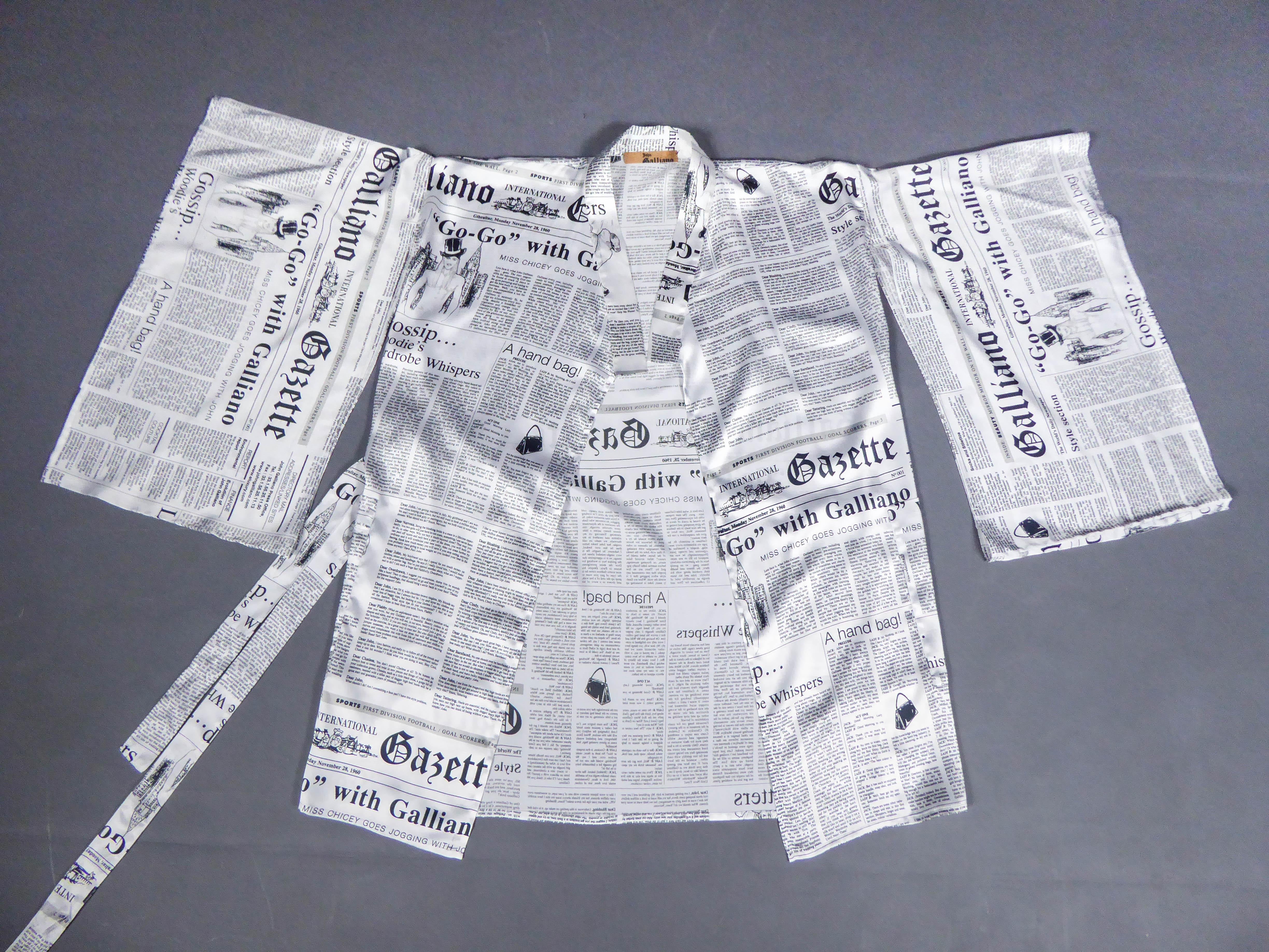 Circa 2000
France

Black and white printed satin kimono dress from John Galliano. White silk satin with humoristic print of newspapers detailing the creator's career, including his date of birth. Wide kimono sleeves and matching belt to tie. Label