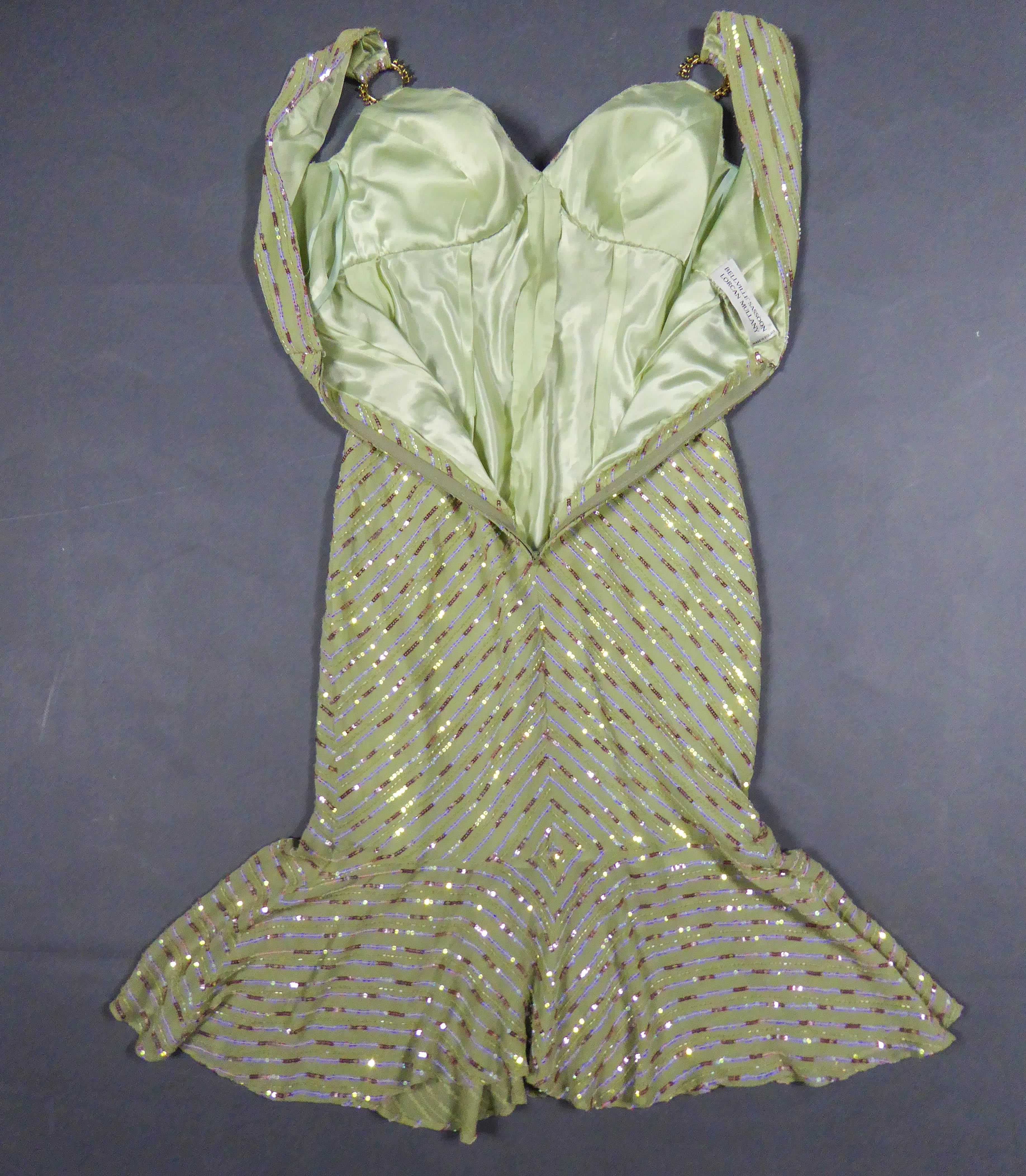 Circa 1990
England

Cocktail or evening dress in pale green celadon silk crepe embroidered with iridescent silver, pink and blue sequins. Dress with large low-cut neckline, sleeveless and high waist. Rhinestone jewelry rings at the level of the
