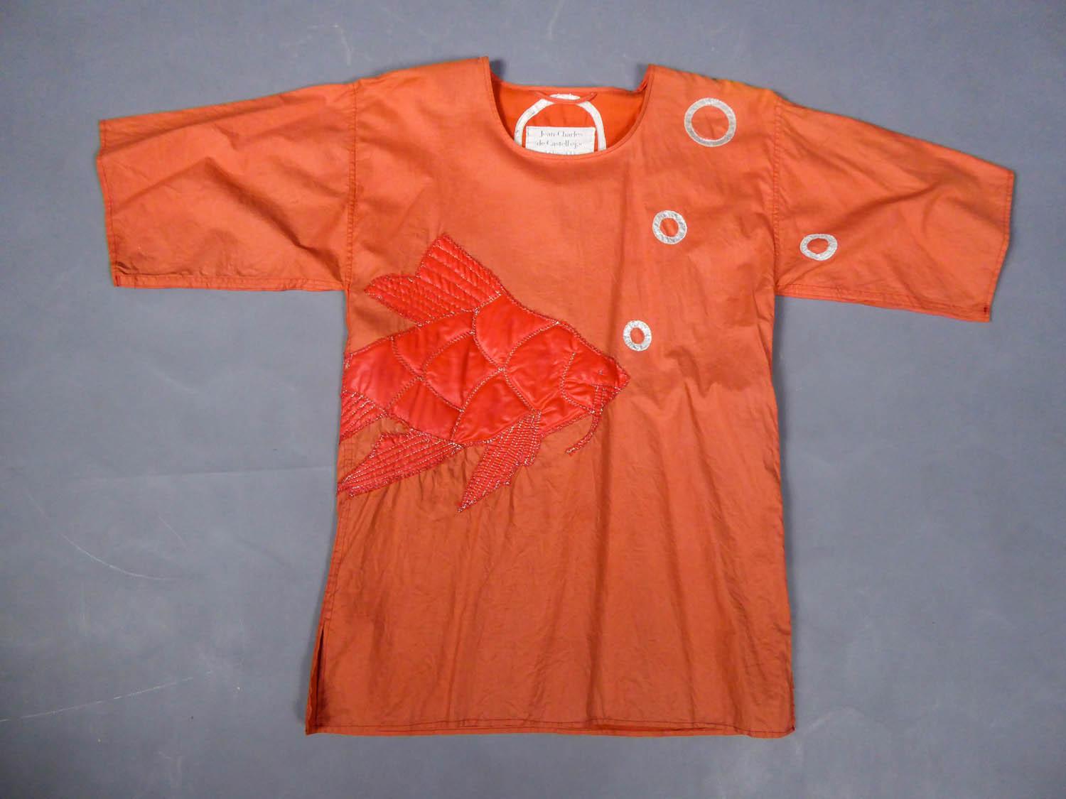 Circa 1990
France

Large Blouse in very fine woven orange cotton and applied with a goldfish with gold stitching and silver circles imitating bubbles. Round neck and 3/4 sleeves, a nod to the creations of Elsa Schiaparelli. Label white background