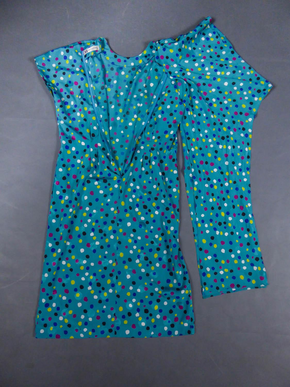 Um 1980
Frankreich

Pierre Balmain Sommerkleid aus blauer Seide mit Tupfen in den Farben Gelb, Rosa, Weiß und Schwarz. Rundhalsausschnitt, kurze Kimono-Ärmel, in der Taille gestrafftes Kleid, das durch eine an der Hüfte gebundene Drapierung betont